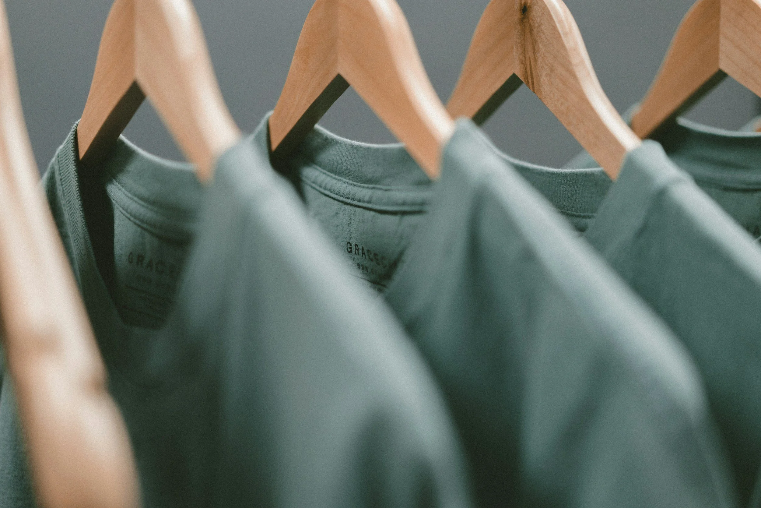 Green T-shirts on wooden hangers