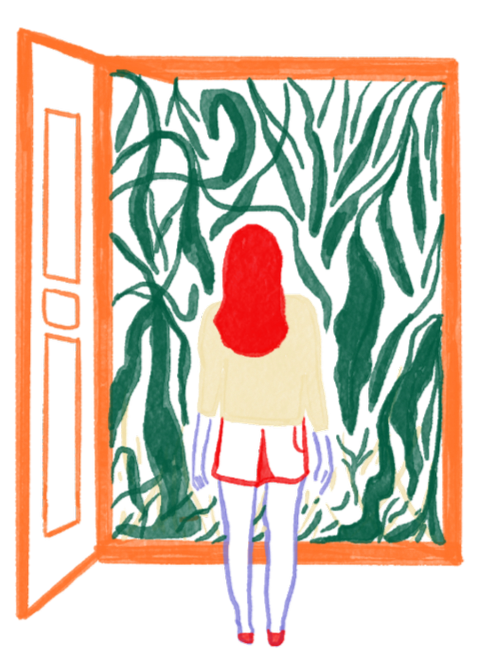 A person with red hair standing in front of a dense green foliage background on a city street, with an orange phone booth to the left.