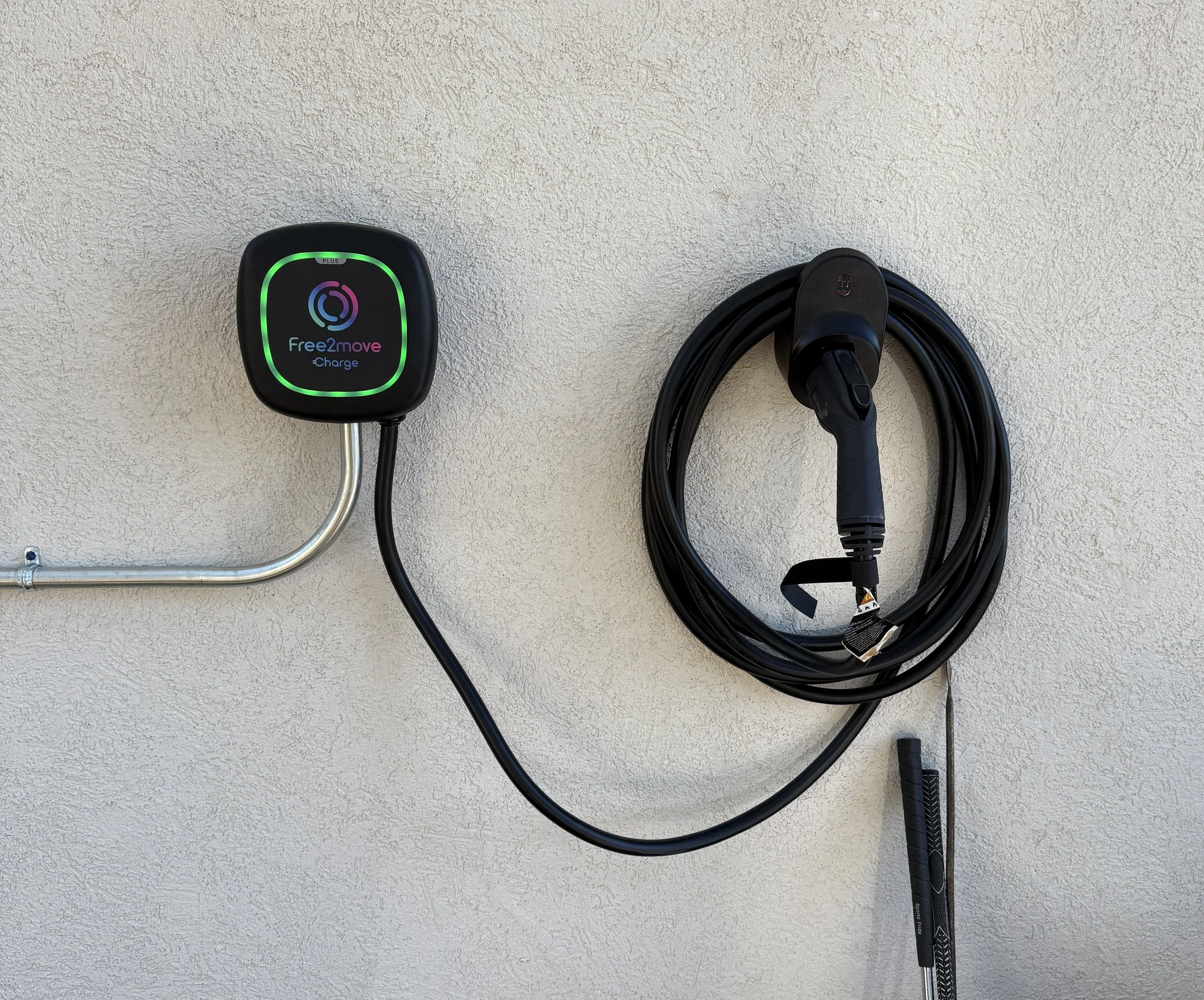 Electric vehicle charging station with a connected charging cable mounted on a white wall.