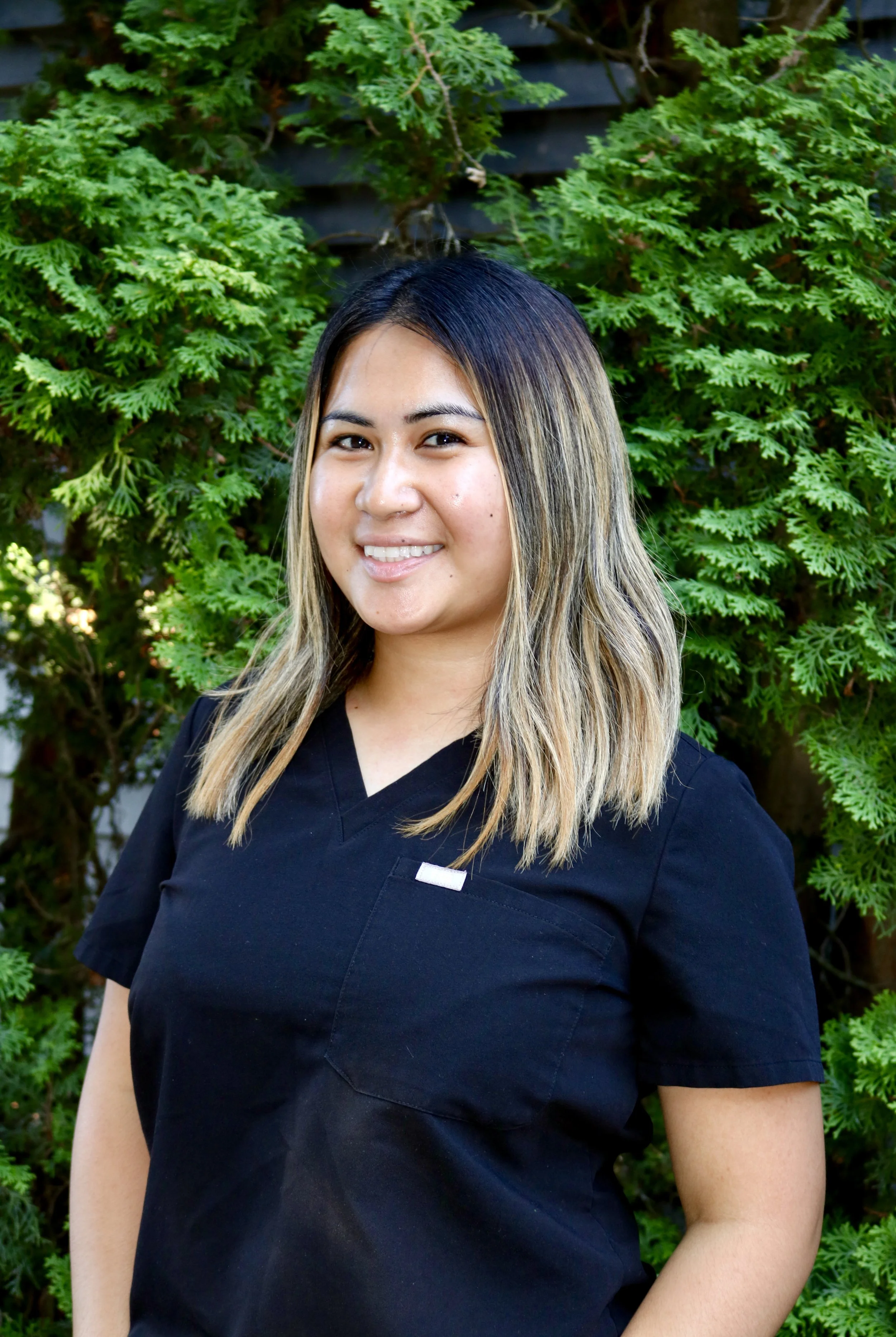 Lexy, a dental assistant, smiling outside the dental clinic.