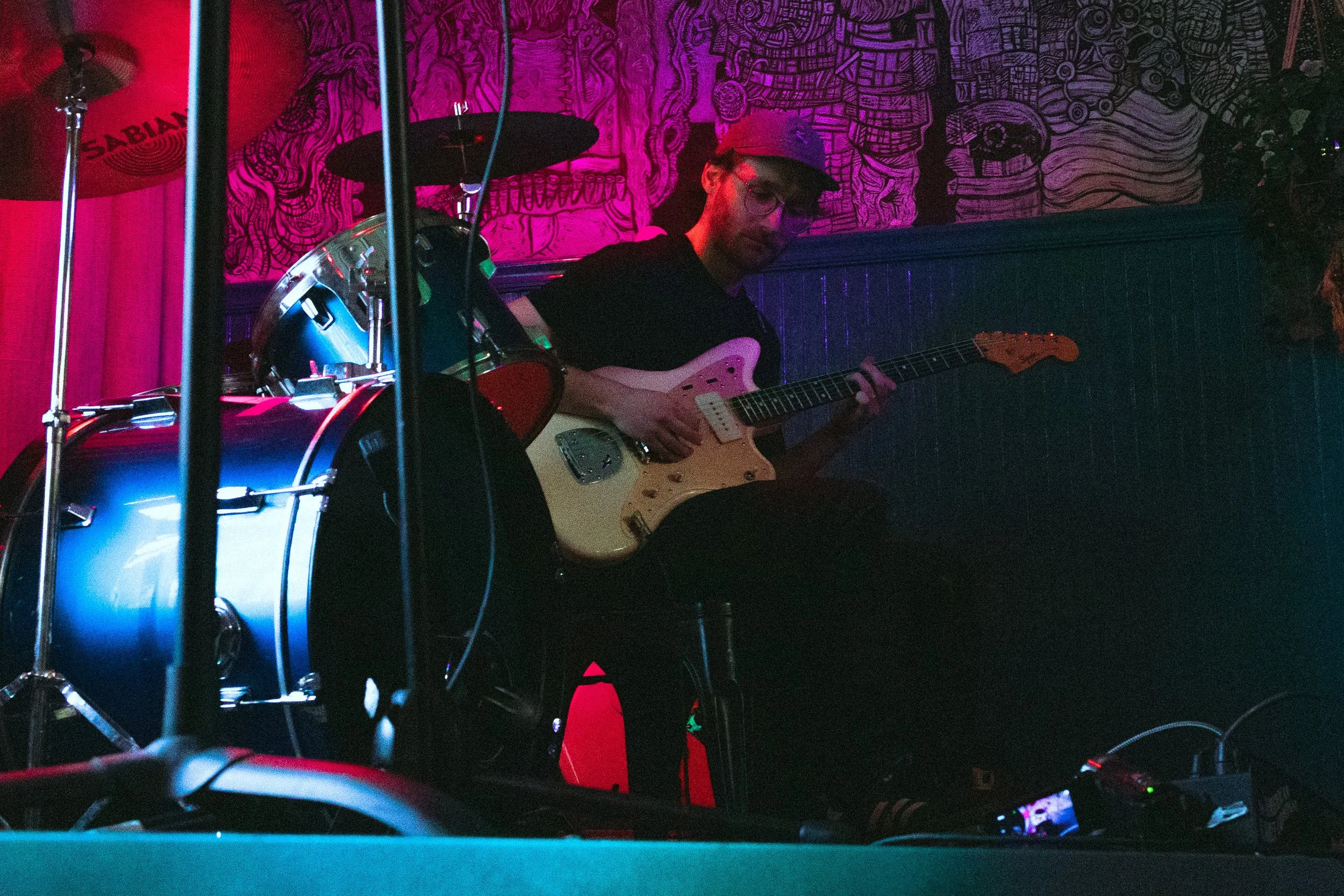 Skyler Waryan playing guitar under stage lighting