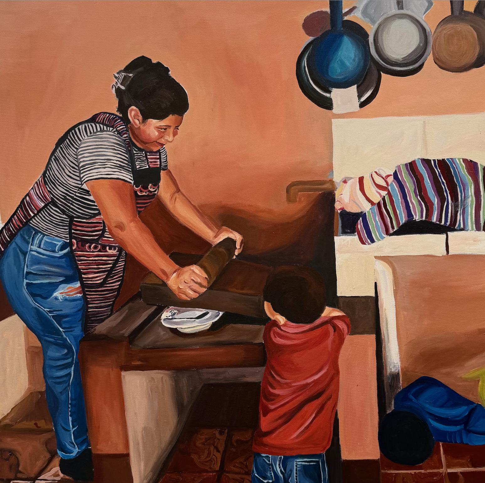 A woman wearing a black and white striped shirt and jeans is rolling dough on a wooden table in a kitchen. A young child in a red hoodie is standing in front of her, watching. There are hanging pots and pans on the wall, and various kitchen items are