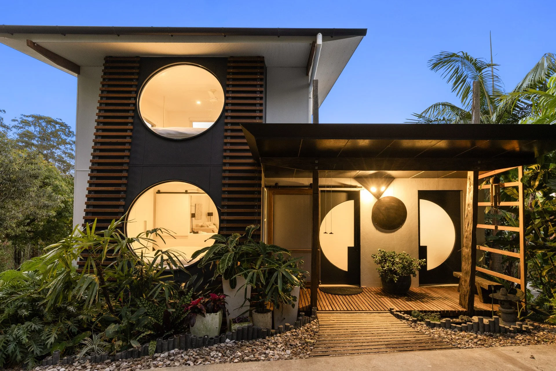 Distinctive circular windows and warm evening lighting give the house its unique character.