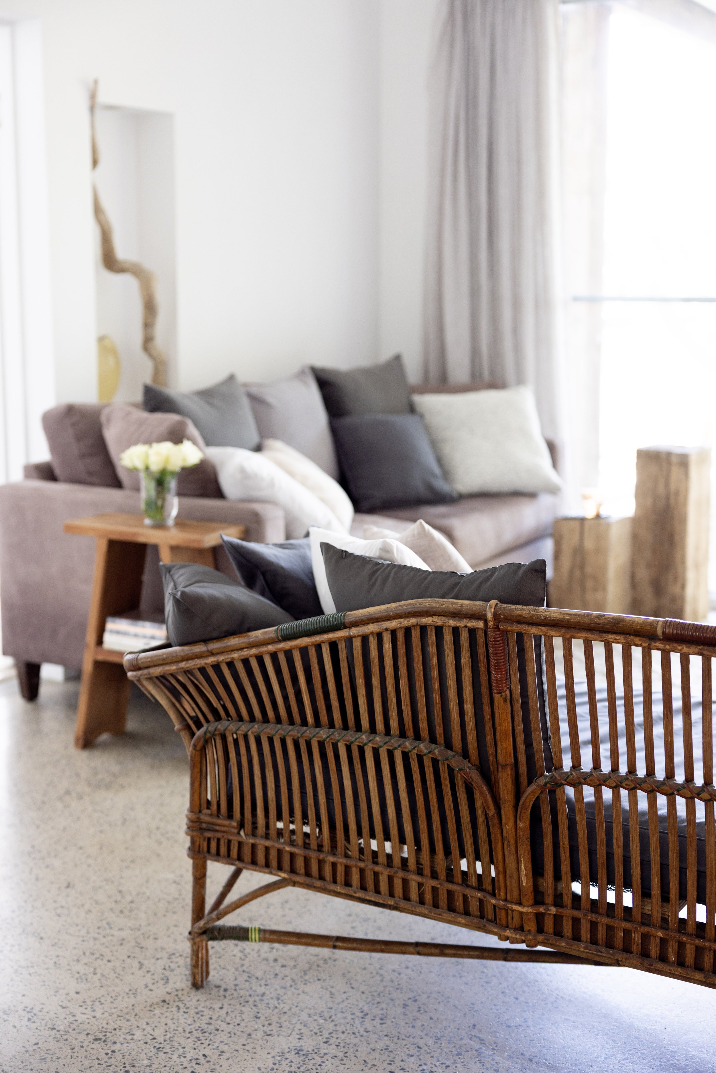 Stylish living room with an antique cane sofa, handwoven wool rug, and serene coastal tones at Haven Tropicana.