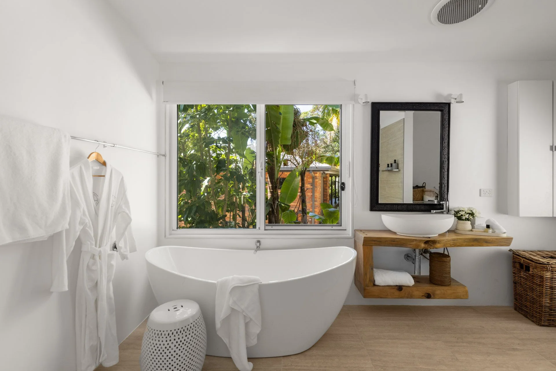 A beautiful, light-filled bathroom with a freestanding bath and leafy garden outlook.