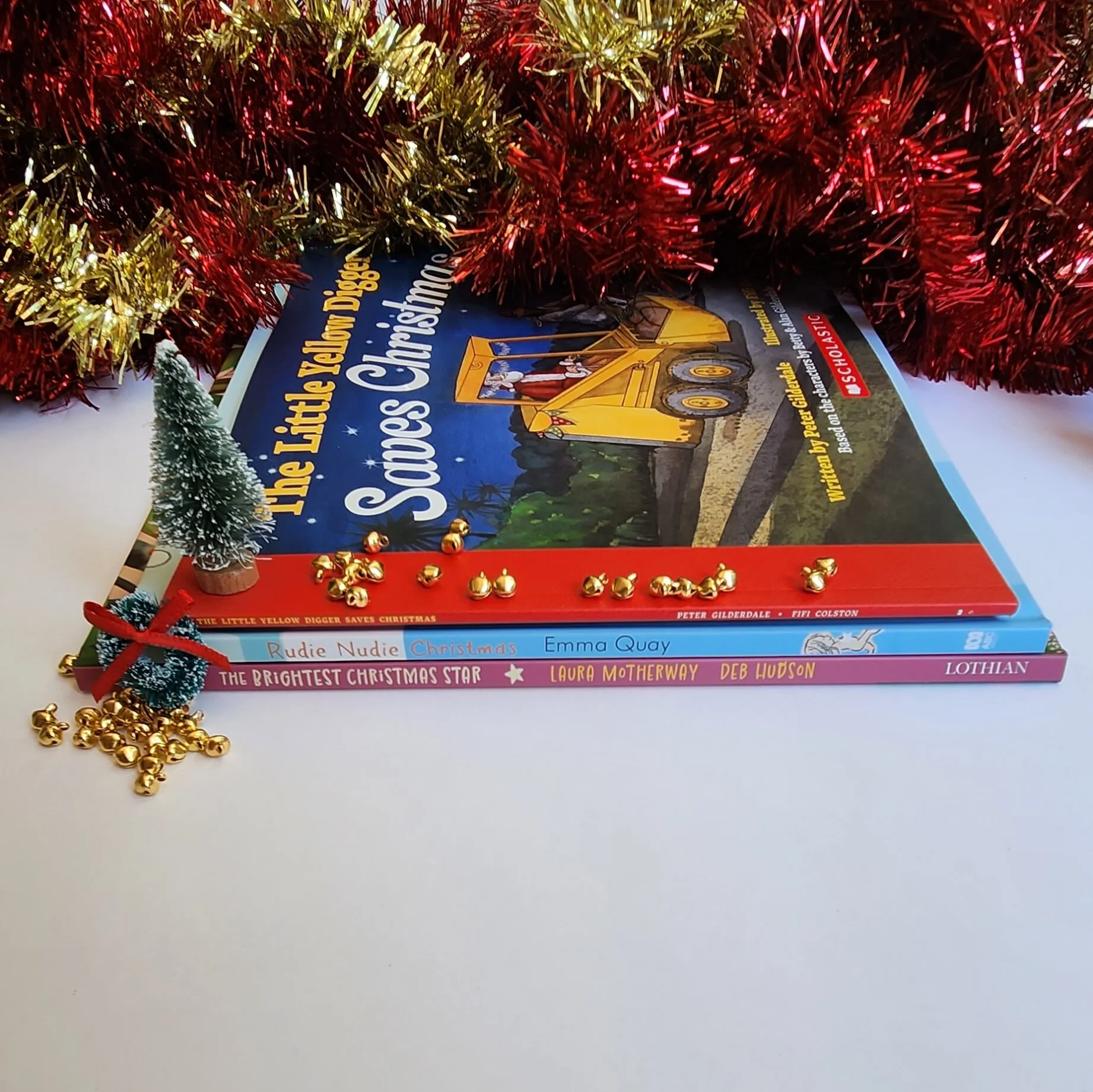 three books displayed with tinsel, chirstmas tree, wreath and bells