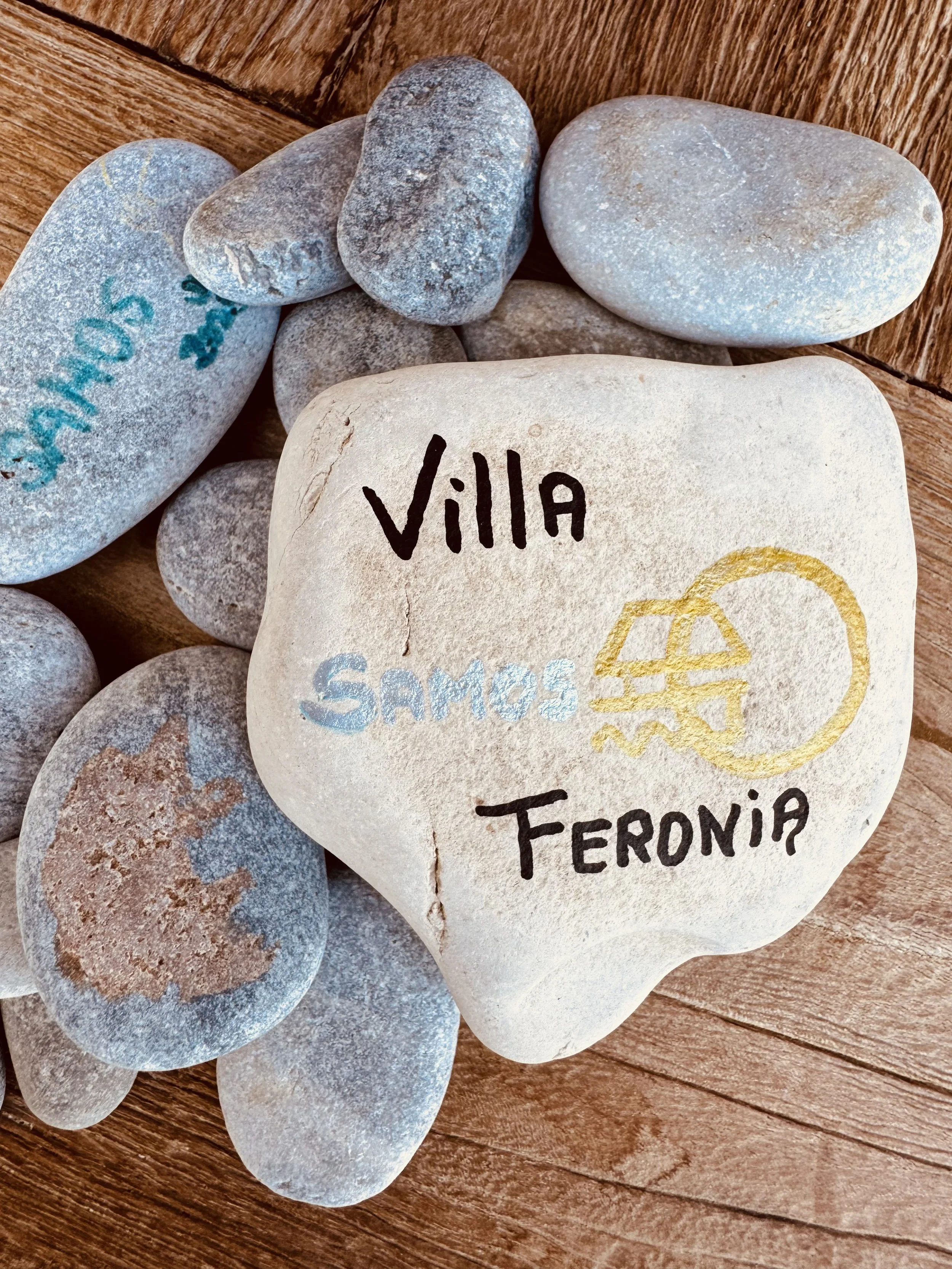 Een steen met de inscriptie 'Villa', omringd door andere stenen op een houten vloer.