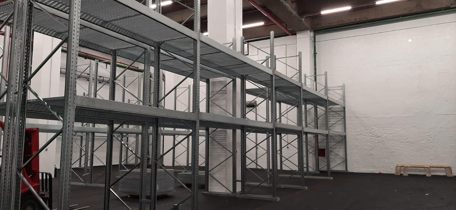 Étagères en métal en cours d'installation dans un espace industriel vide.