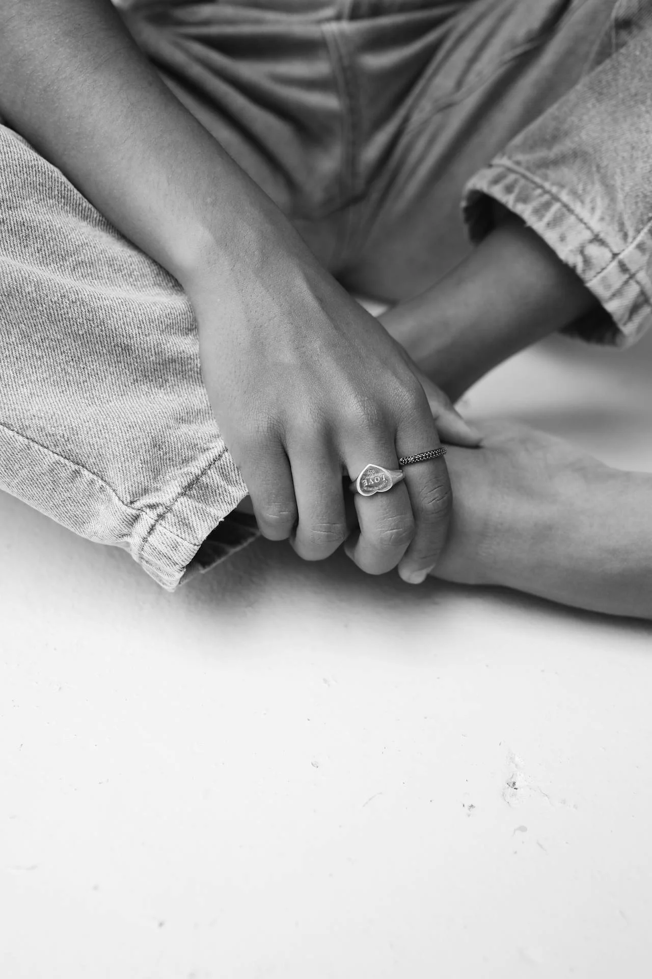 Två händer som håller varandra, en person med ringar om fingret, i svartvitt.