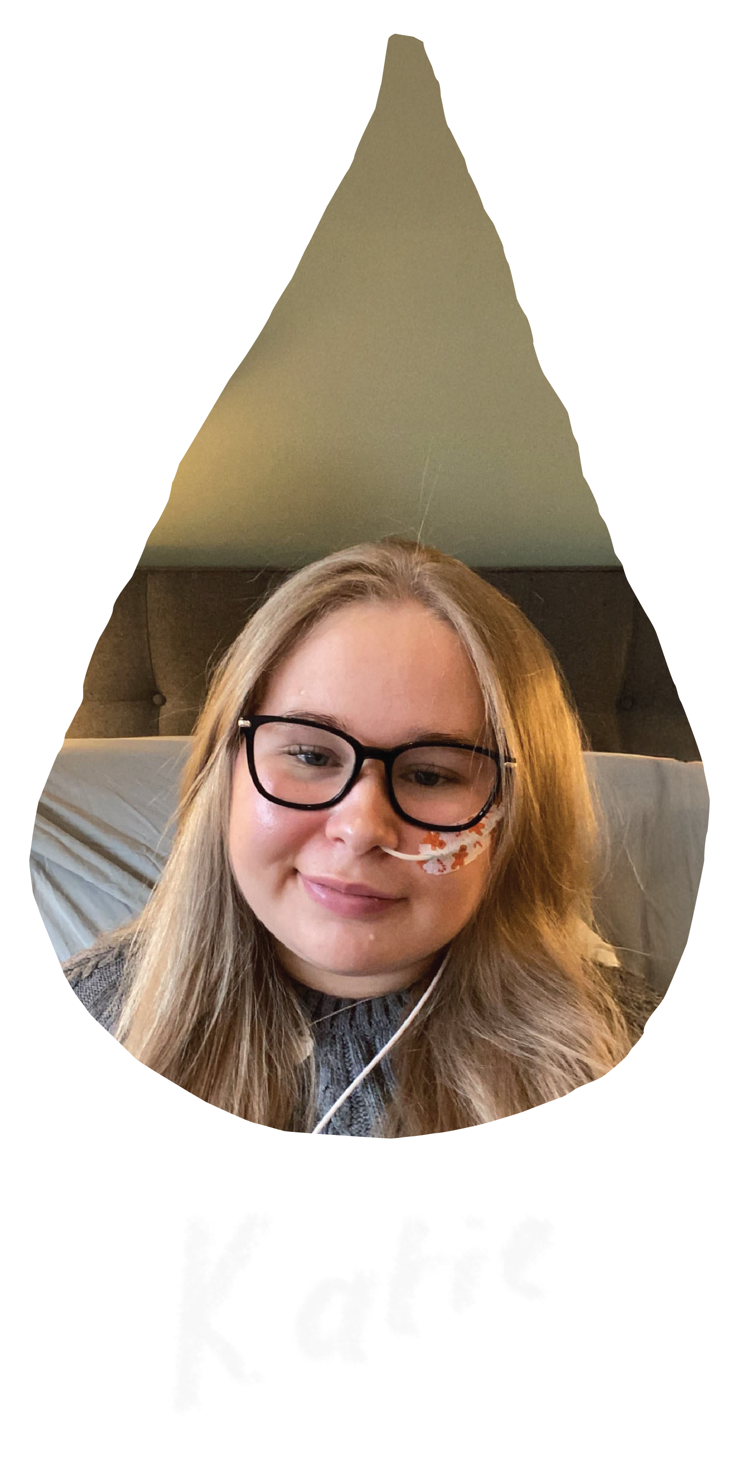 A raindrop shaped image of Emily, a young white woman with wavy brown hair wearing a pale blue short-sleeved dress, is standing in the sunlight in front of bushes and bright pink flowers and smiling.