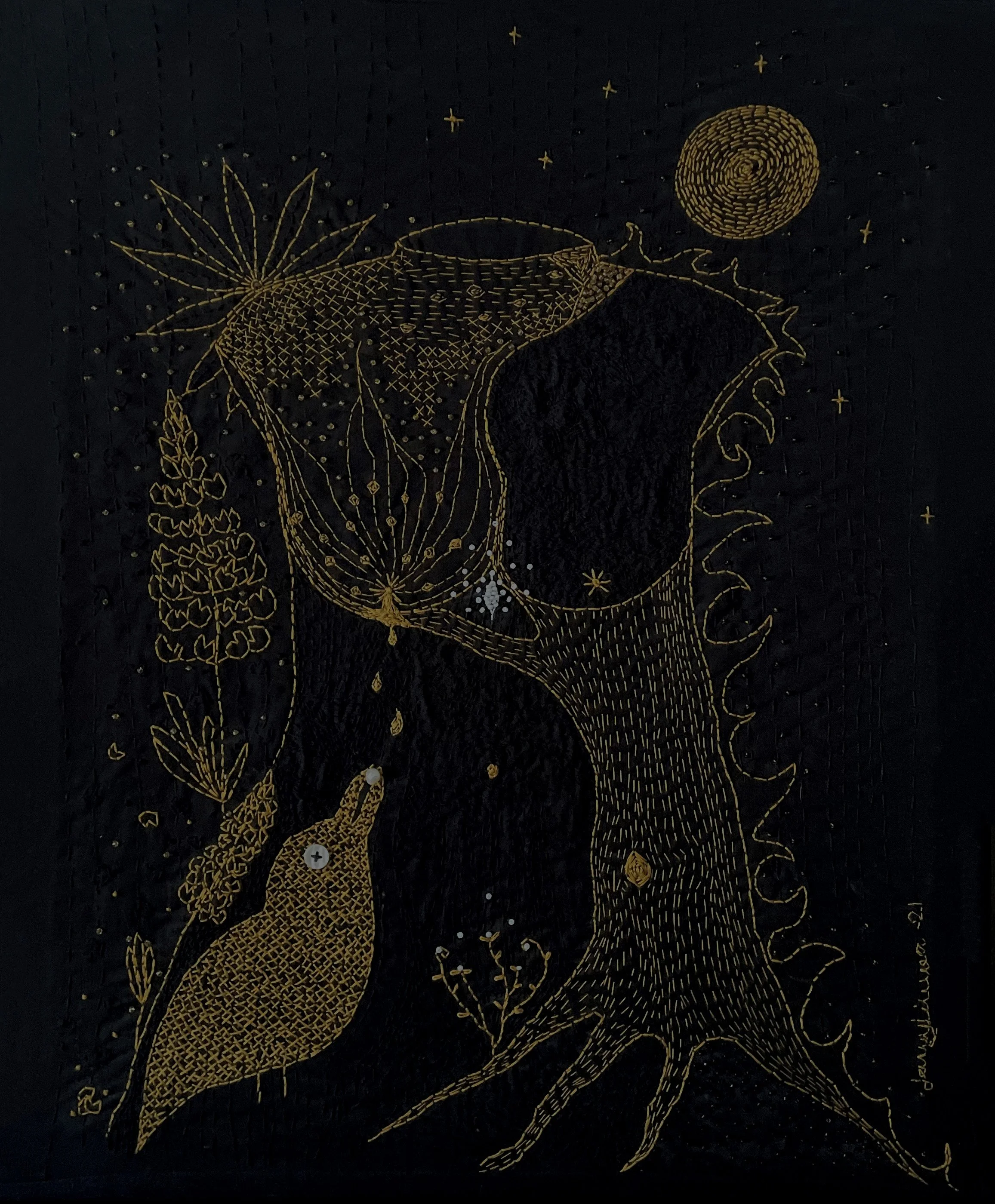 A female torso embroidered in yellow on black fabric. Part of the body is a tree trunk with roots going into the ground, and fire, lupine flowers and leaves, and a full moon surround her. One breast drips milk onto a corvid bird.