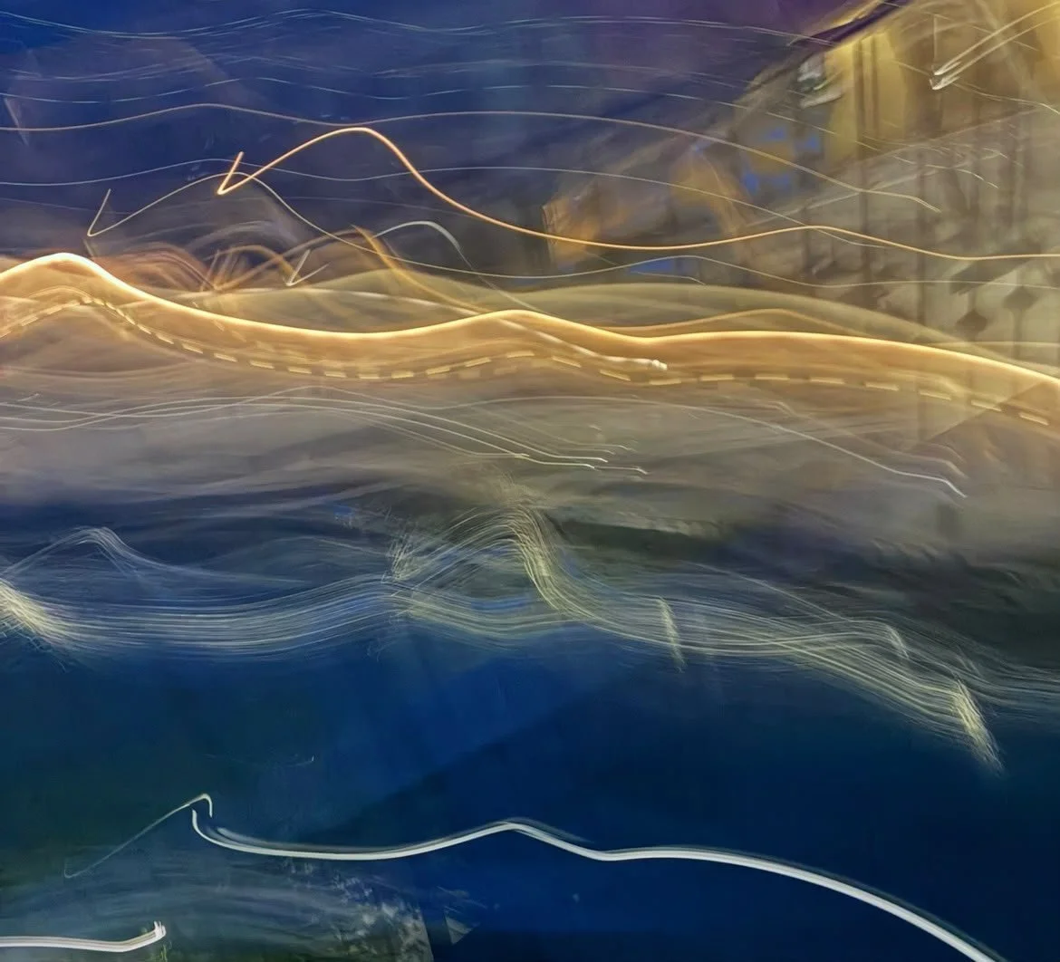 An abstract photograph with a blue background and wavy overlapping light trails.