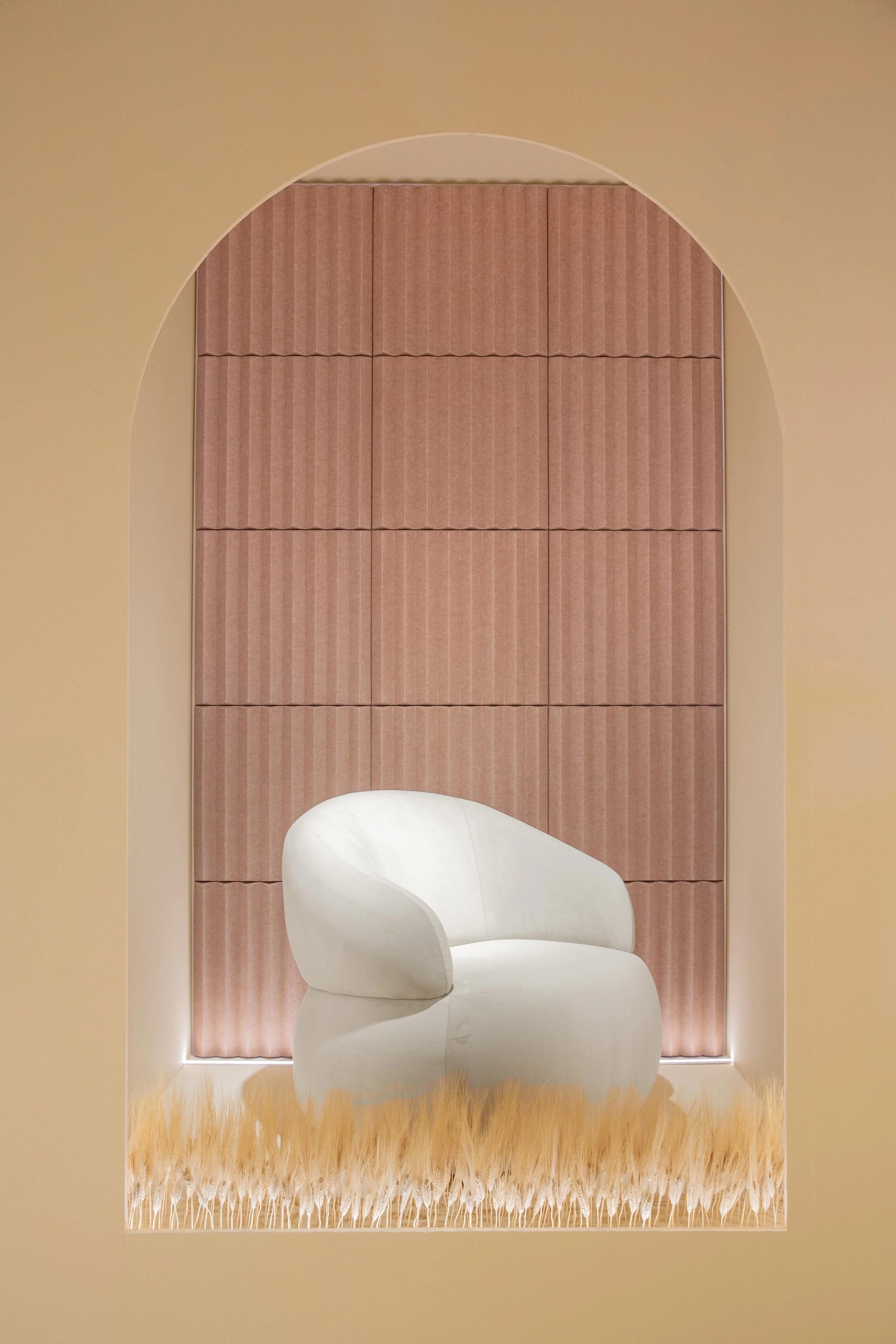 Silla blanca moderna en una habitación con paredes beige, cortinas rosas y alfombra de felpa beige.