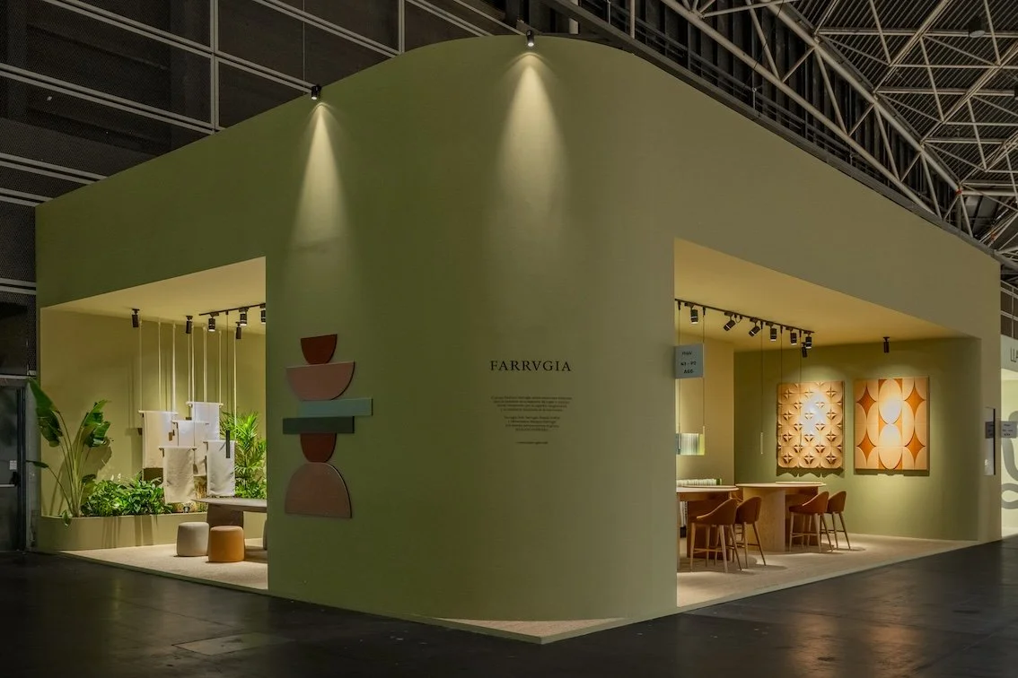 Stand de exhibición de diseño y mobiliario con paredes en color verde, decoración moderna y áreas con plantas.