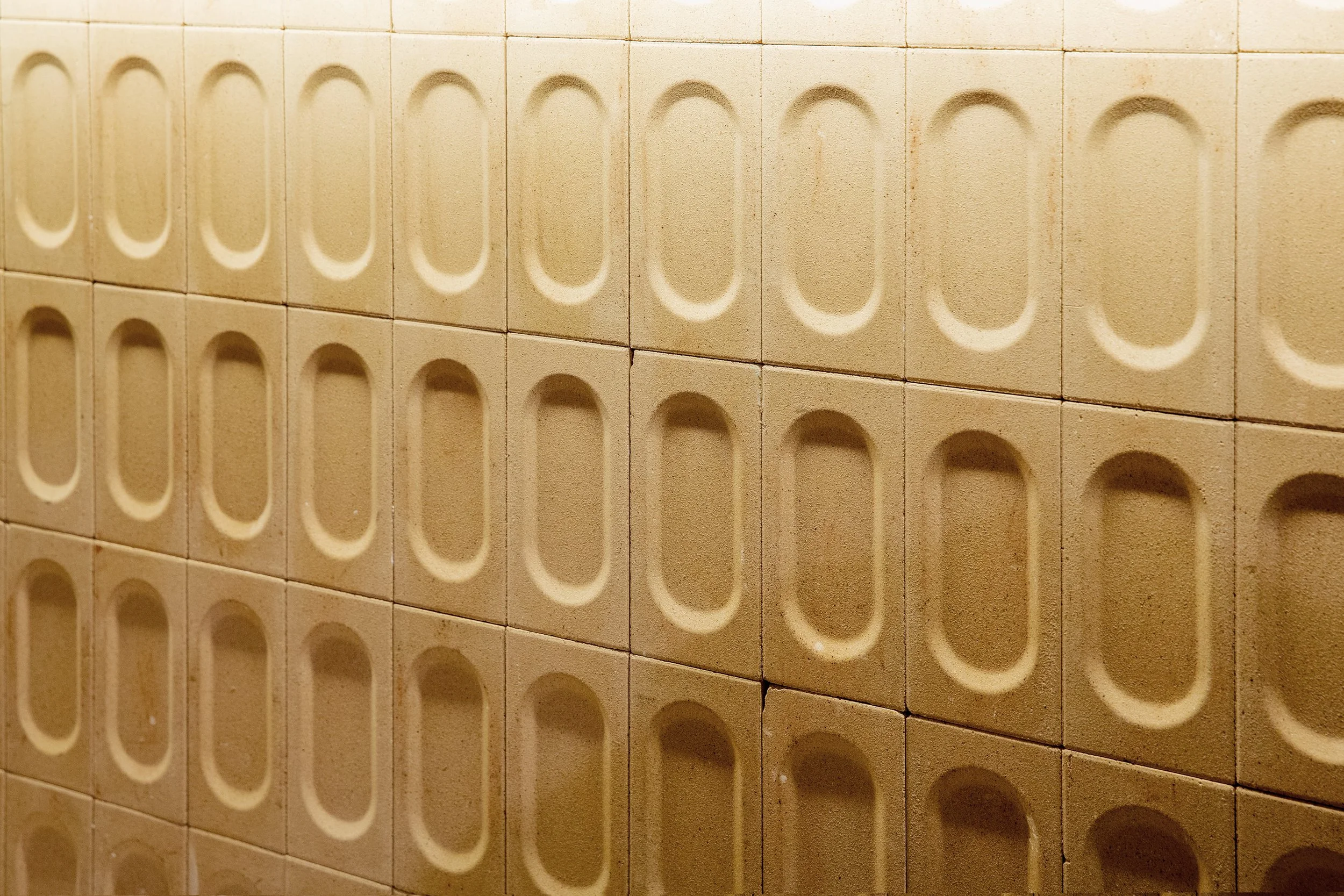 Ladrillos beige con diseño de arcos en relieve en la pared.