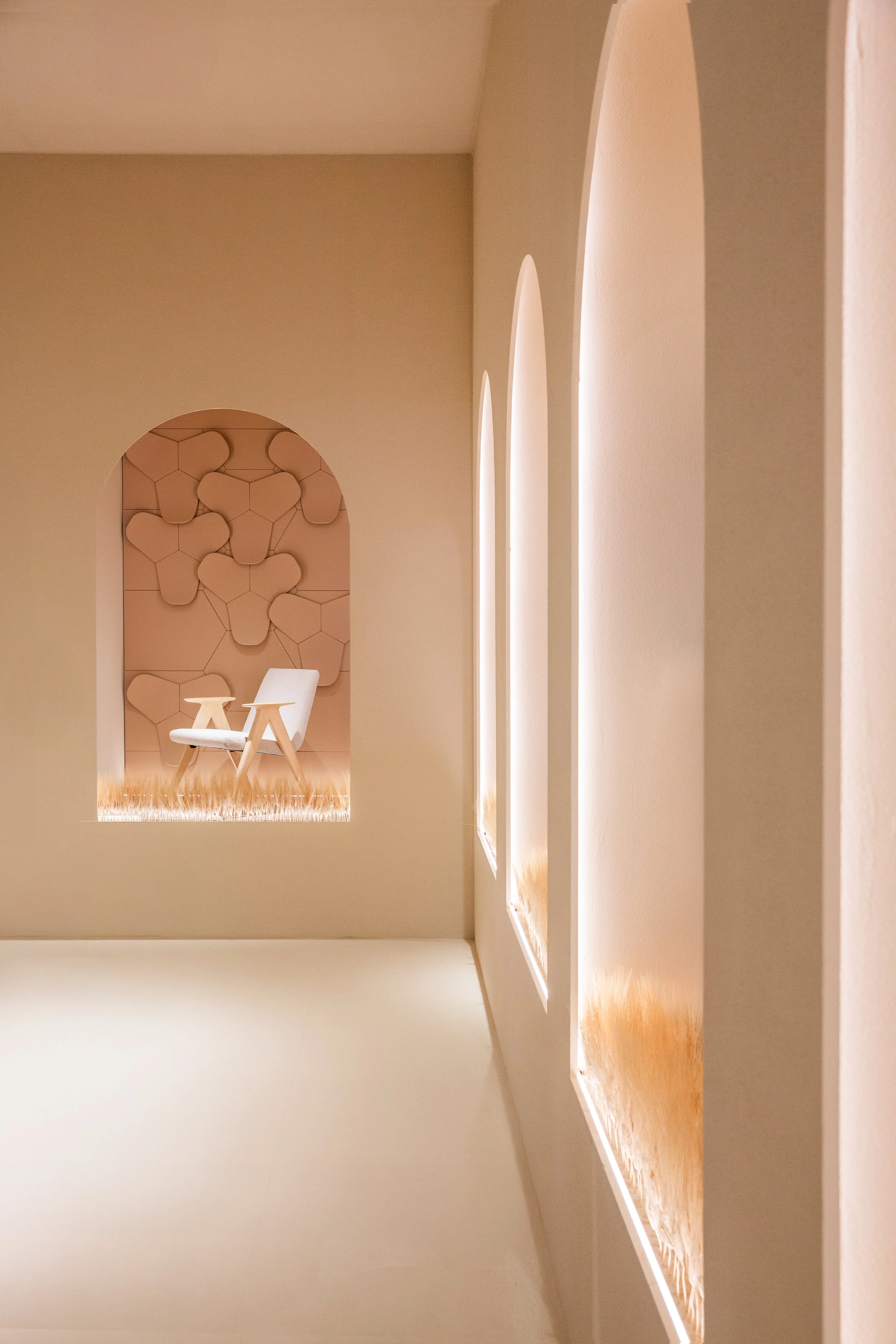 Interior de un espacio con paredes blancas y decorativas, con una silla blanca y un fondo con patrón geométrico en tonos neutros