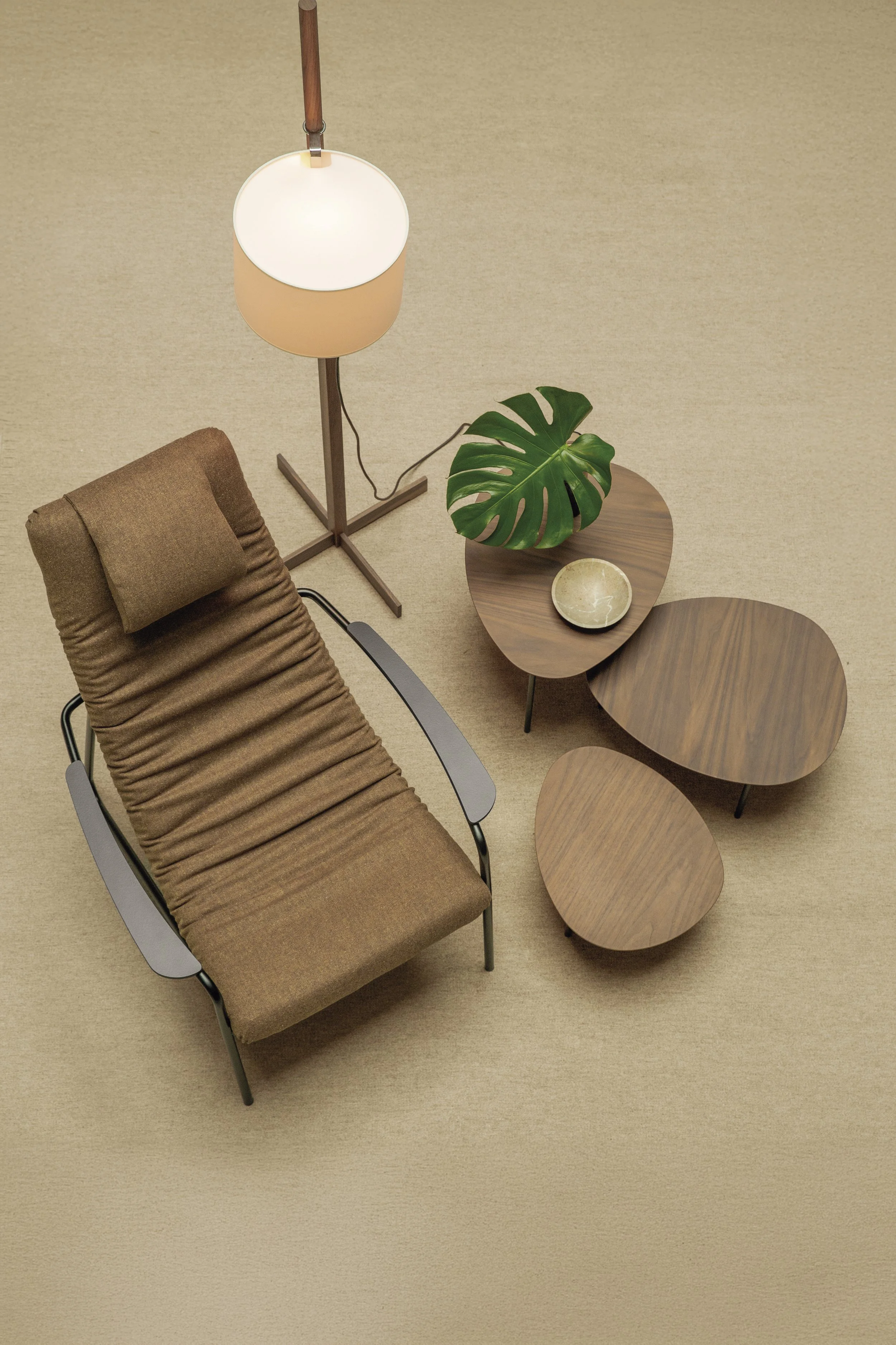 Vista aérea de una sala moderna con sillón, lámpara de pie, mesa con maceta y plato, y una mesa auxiliar.