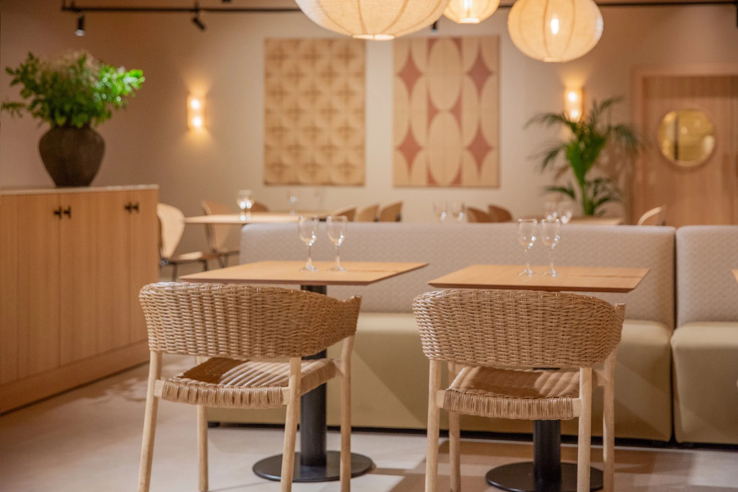 Interior de un restaurante con mesas y sillas de madera, decoraciones en las paredes y lámparas colgantes.