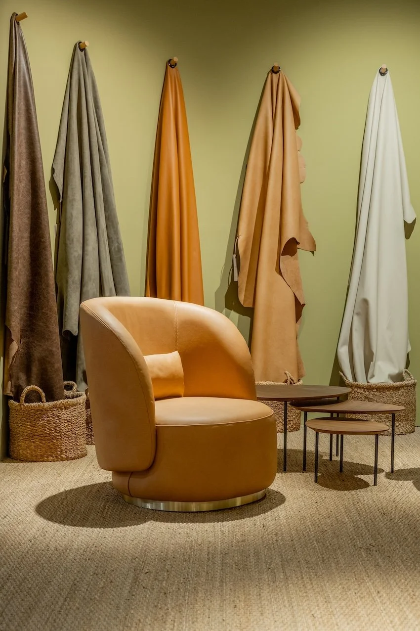 Silla de cuero beige en una habitación con cortinas de diferentes colores colgadas en la pared.