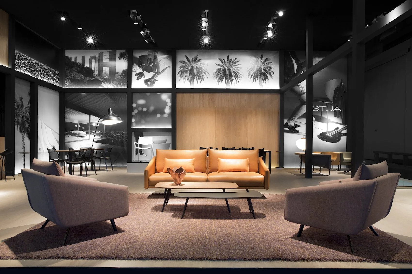 Interior moderno de sala de estar con sillones, sofá y mesa de centro, decorada con fotos en blanco y negro de palmeras y objetos culturales.