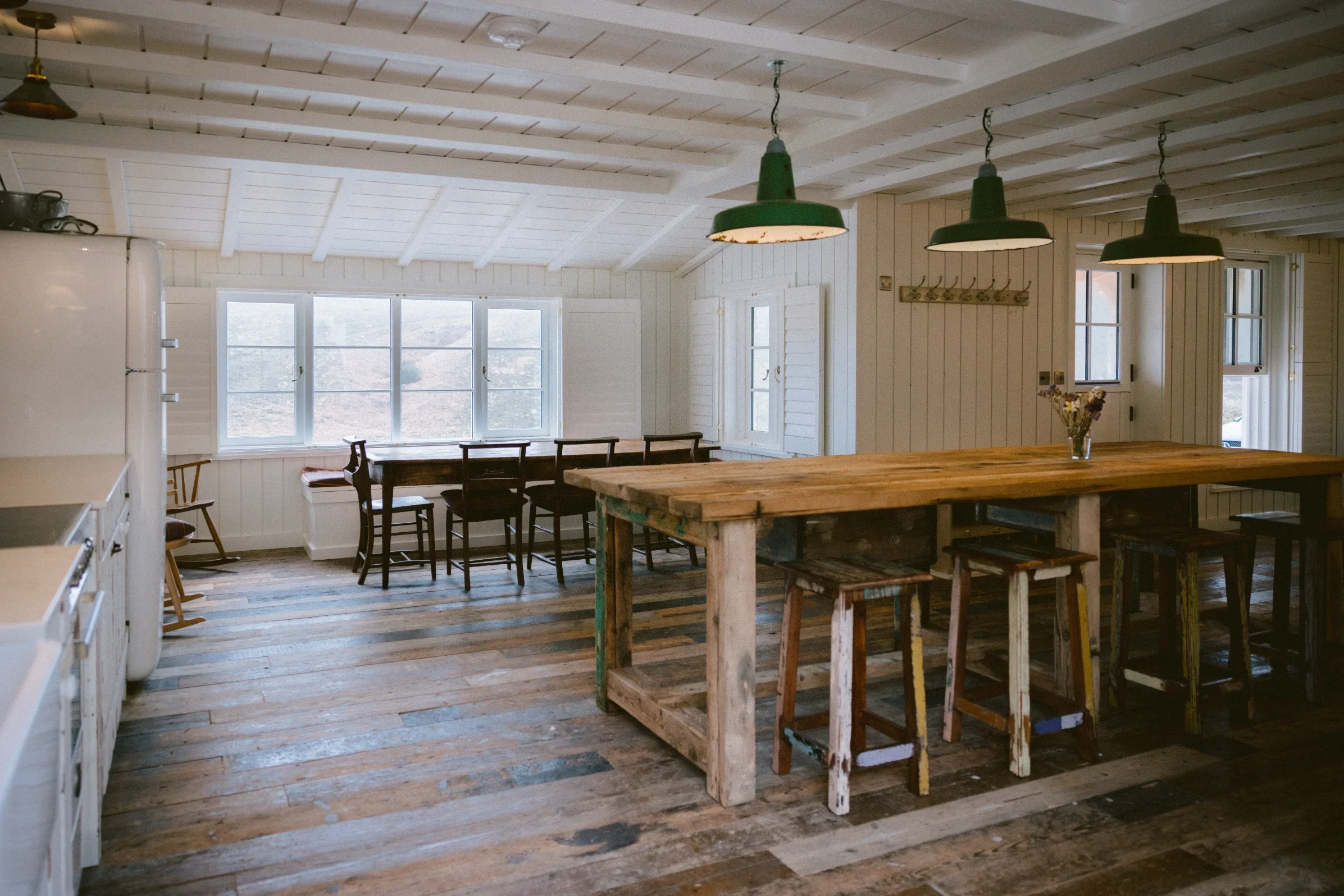 Open-plan kitchen with full-width windows framing the Cornish valley, reclaimed floor and painted tongue-and-groove walls, Cornwall