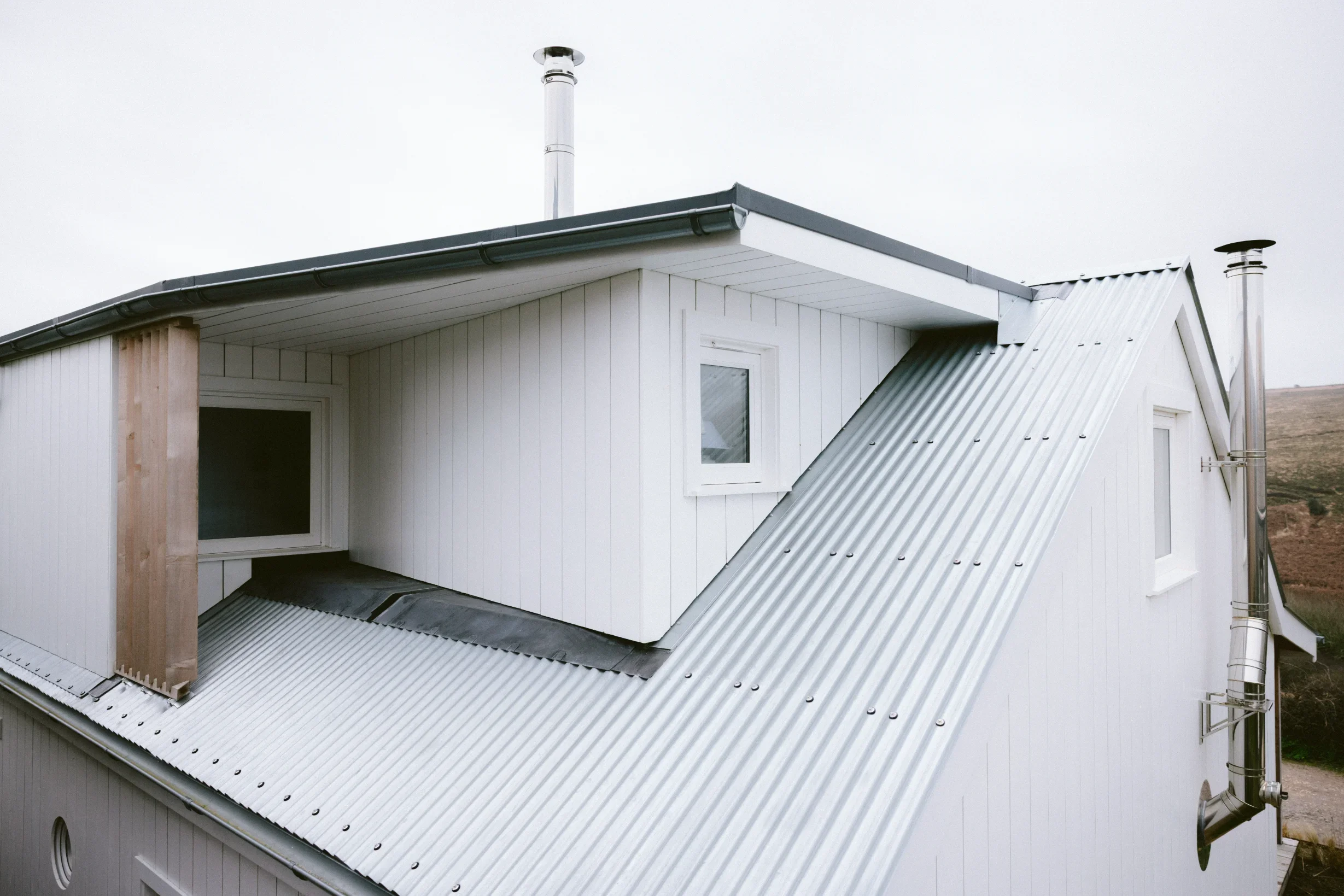 Corrugated metal sheet roof with dormer windows and metal flue, fully rebuilt as part of coastal structure conversion, Cornwall