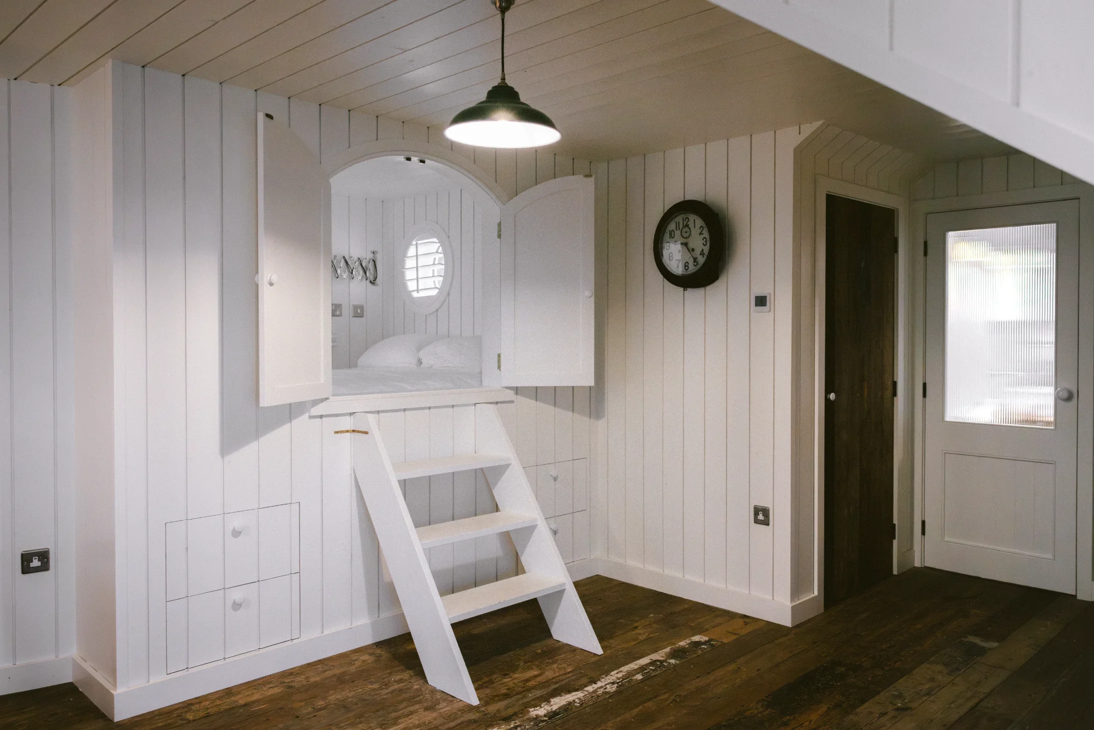 Bespoke built-in bunk bed with arched surround and circular porthole window, custom joinery throughout Cornwall conversion