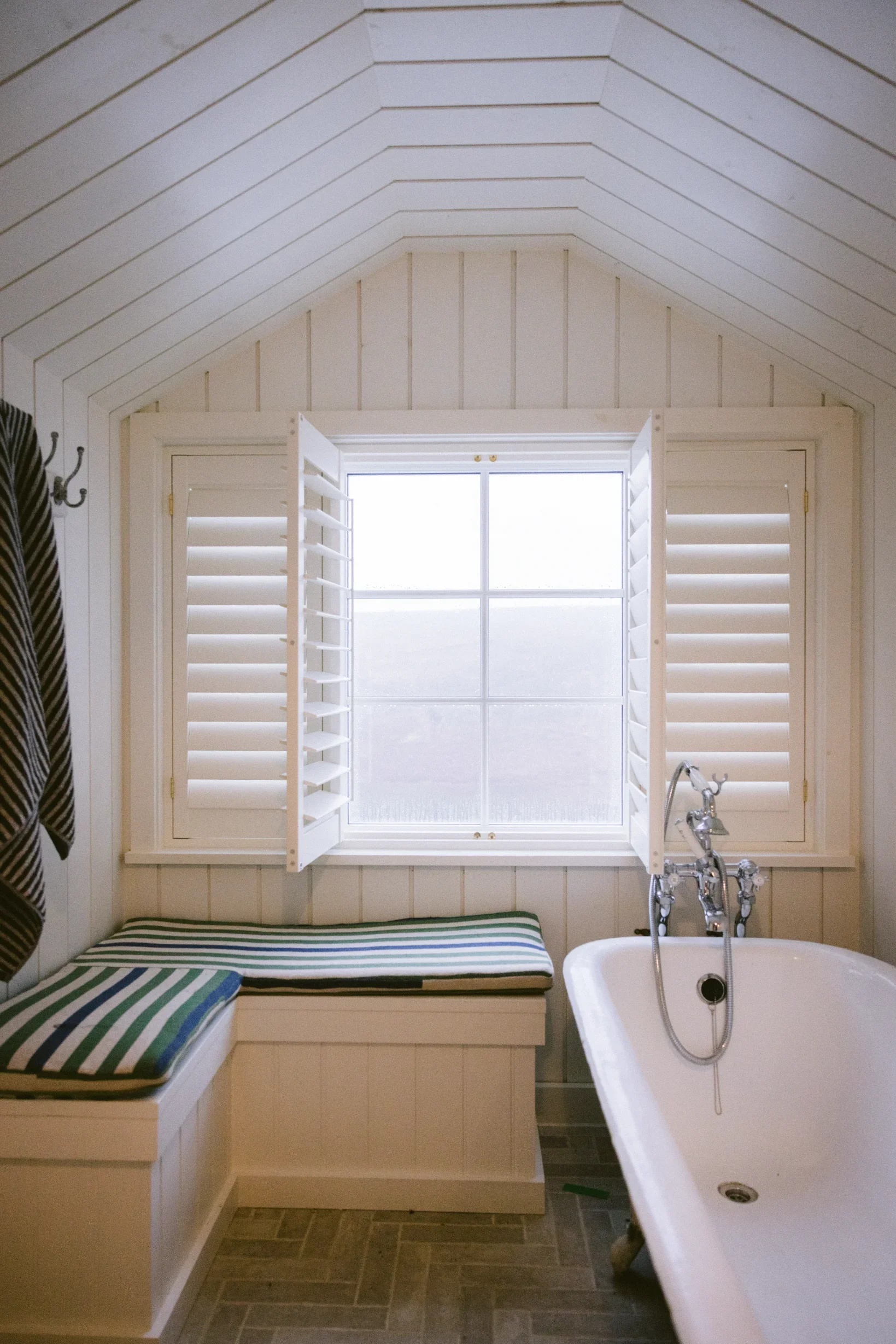 Reclaimed clawfoot bath with vaulted tongue-and-groove ceiling and plantation shutters, Chapel Porth conversion, Cornwall