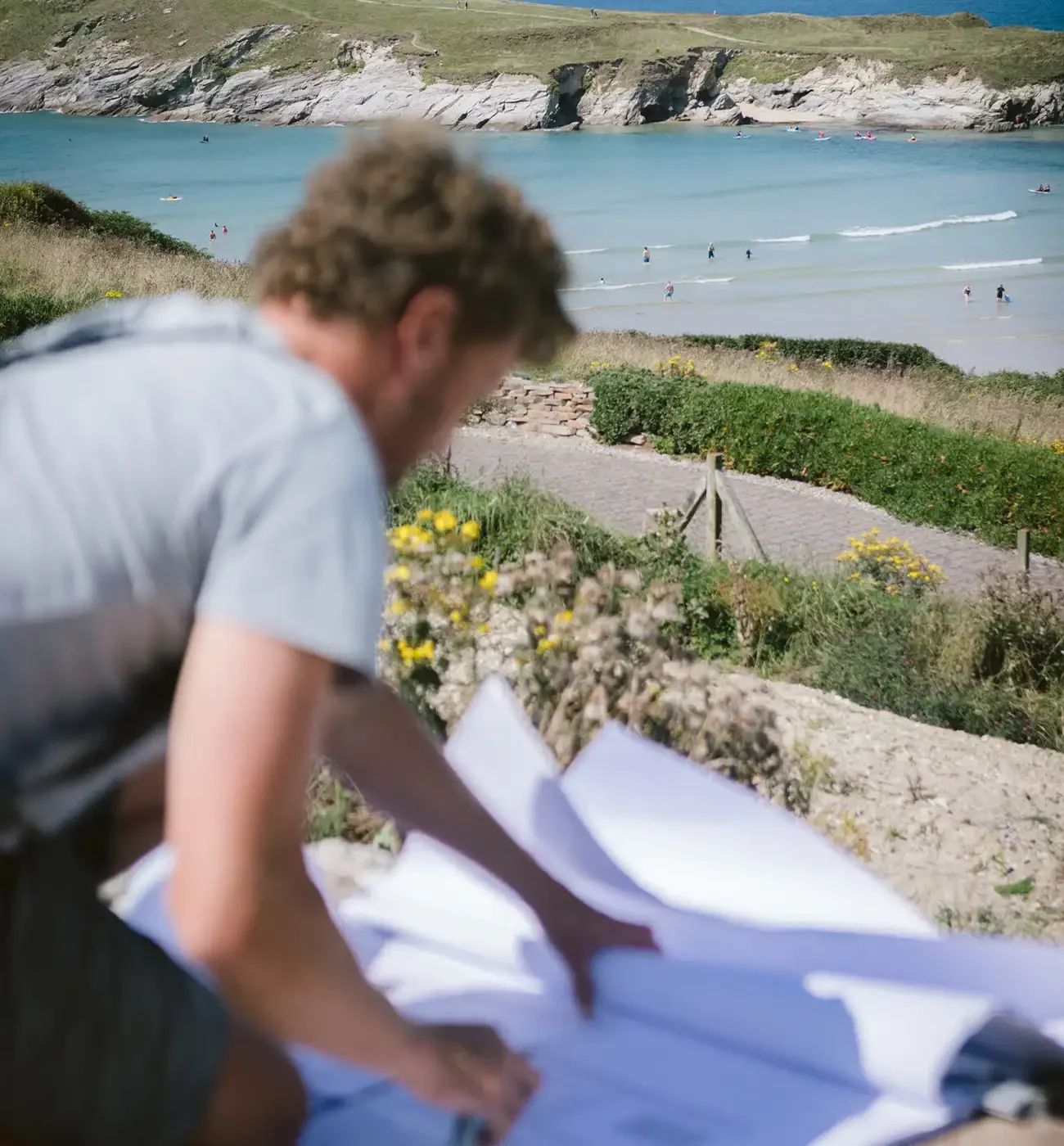 Elements Build reviewing architectural drawings on site overlooking a Cornish bay