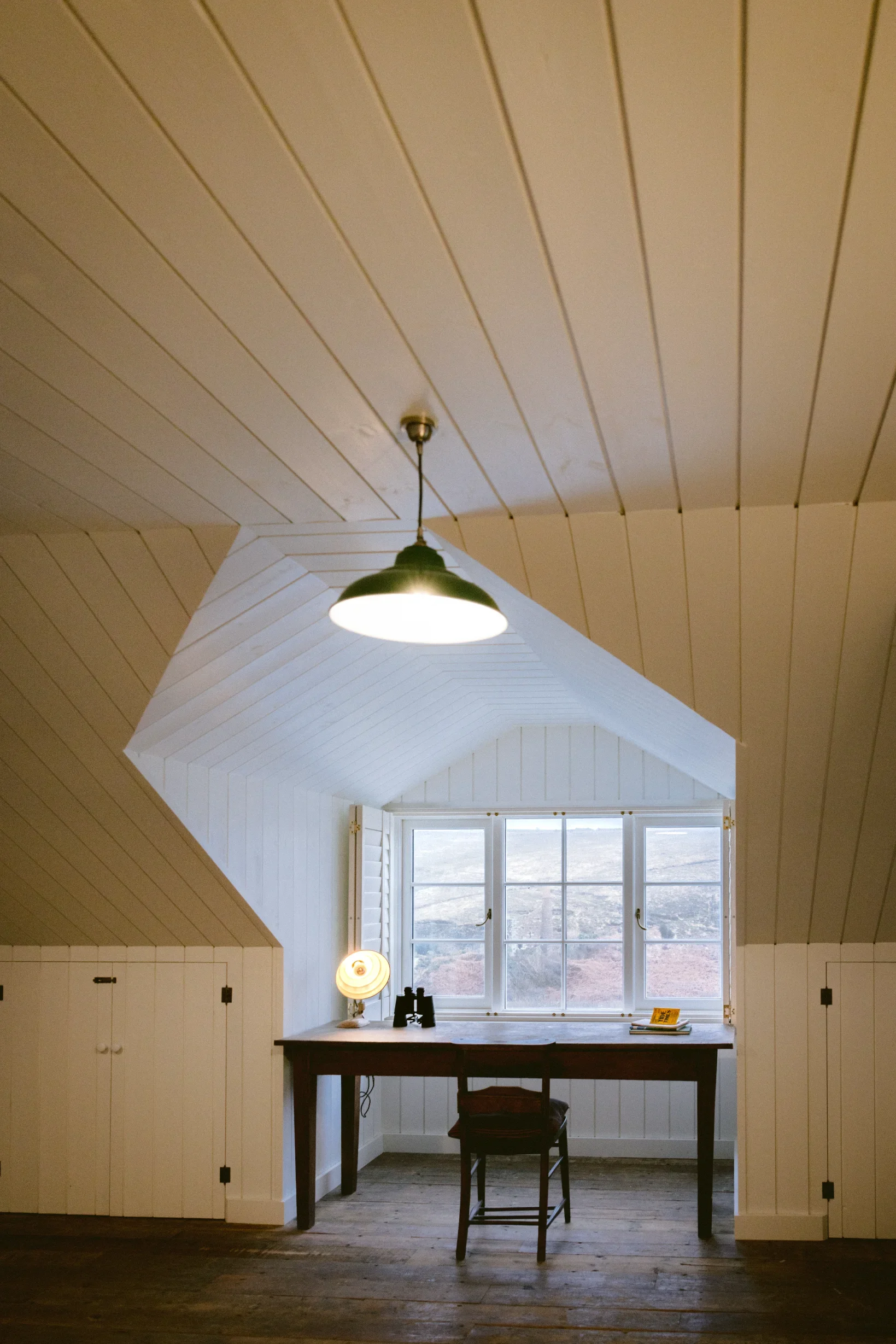 Upstairs study with reclaimed chapel timber flooring, tongue-and-groove lined walls and framed coastal view, Cornwall conversion