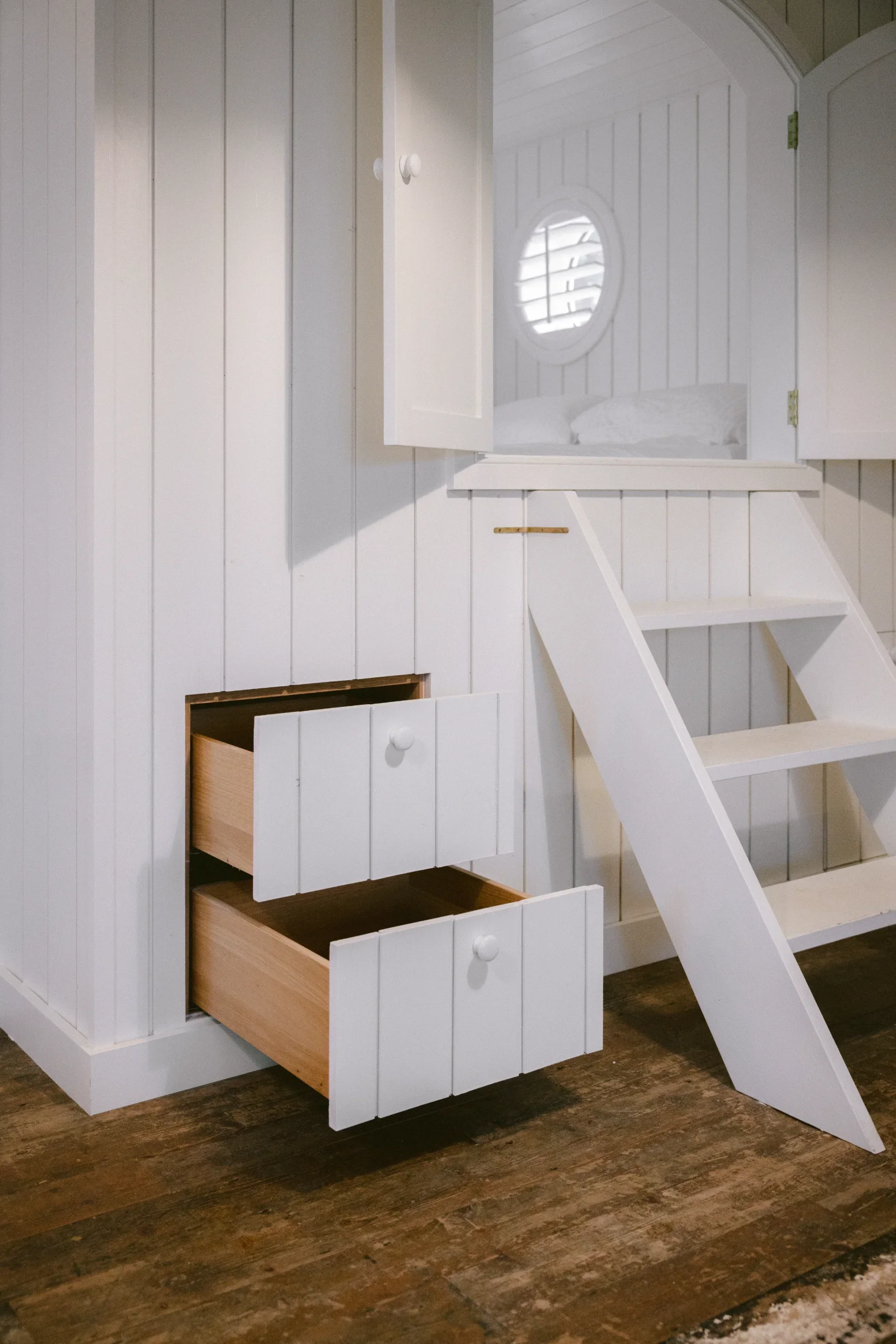 Bespoke white-painted staircase with custom built-in storage drawers and mezzanine bunk, heritage conversion Cornwall