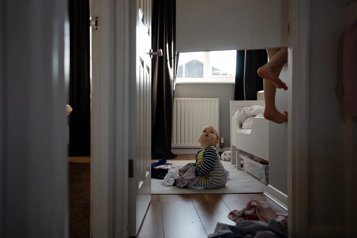 baby watches older sibling crawling up into a cupboard