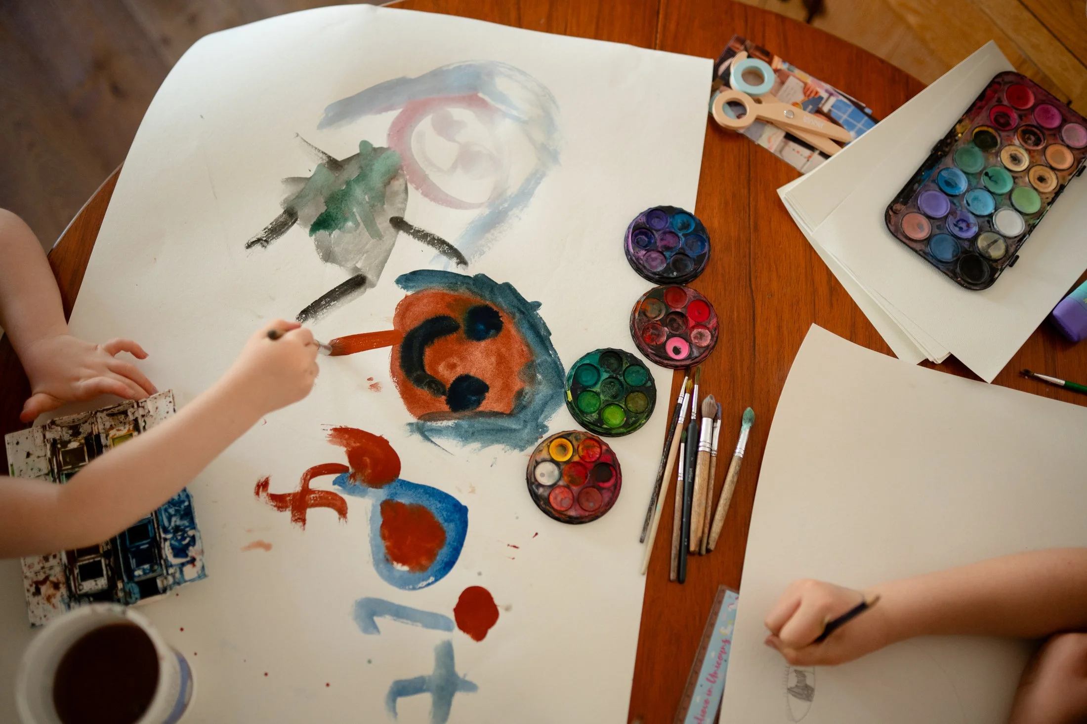 children doing paintings of people on large rolls of paper with watercolours