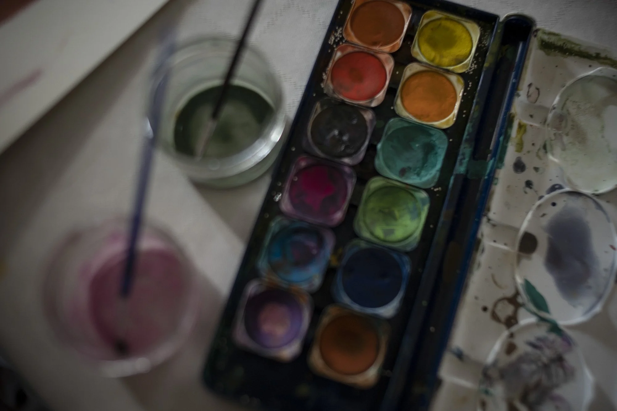 used watercolour set with paintbrushes next to it on a table