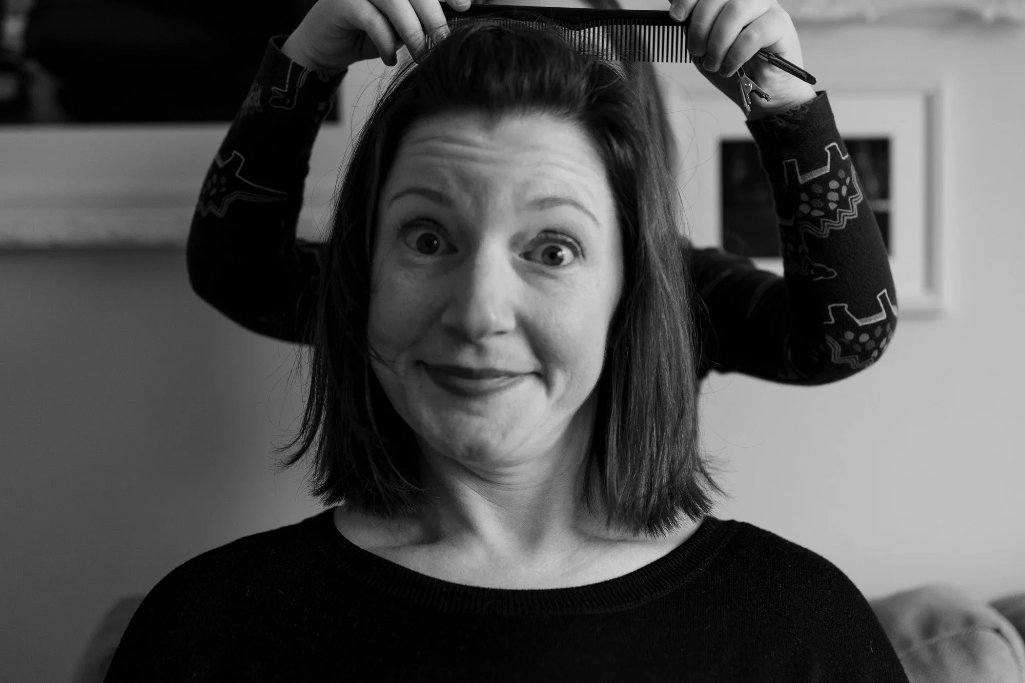 mother with a funny look on her face while child cuts her hair