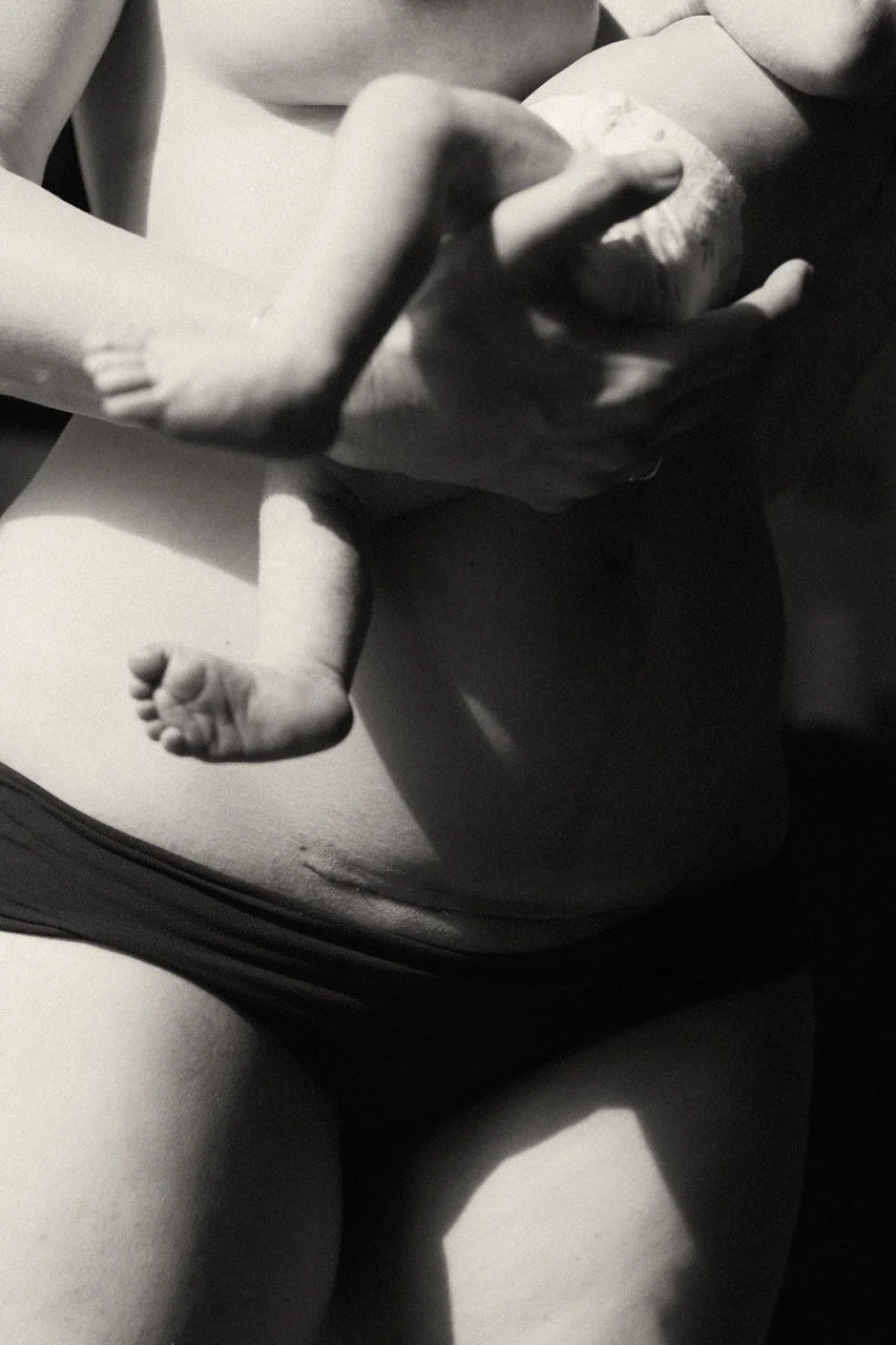 A postpartum mother holds her newborn against her body, c-section scar visible — honest documentary photography of birth, recovery and the unseen strength of motherhood. Tokyo.Paris.Saigon