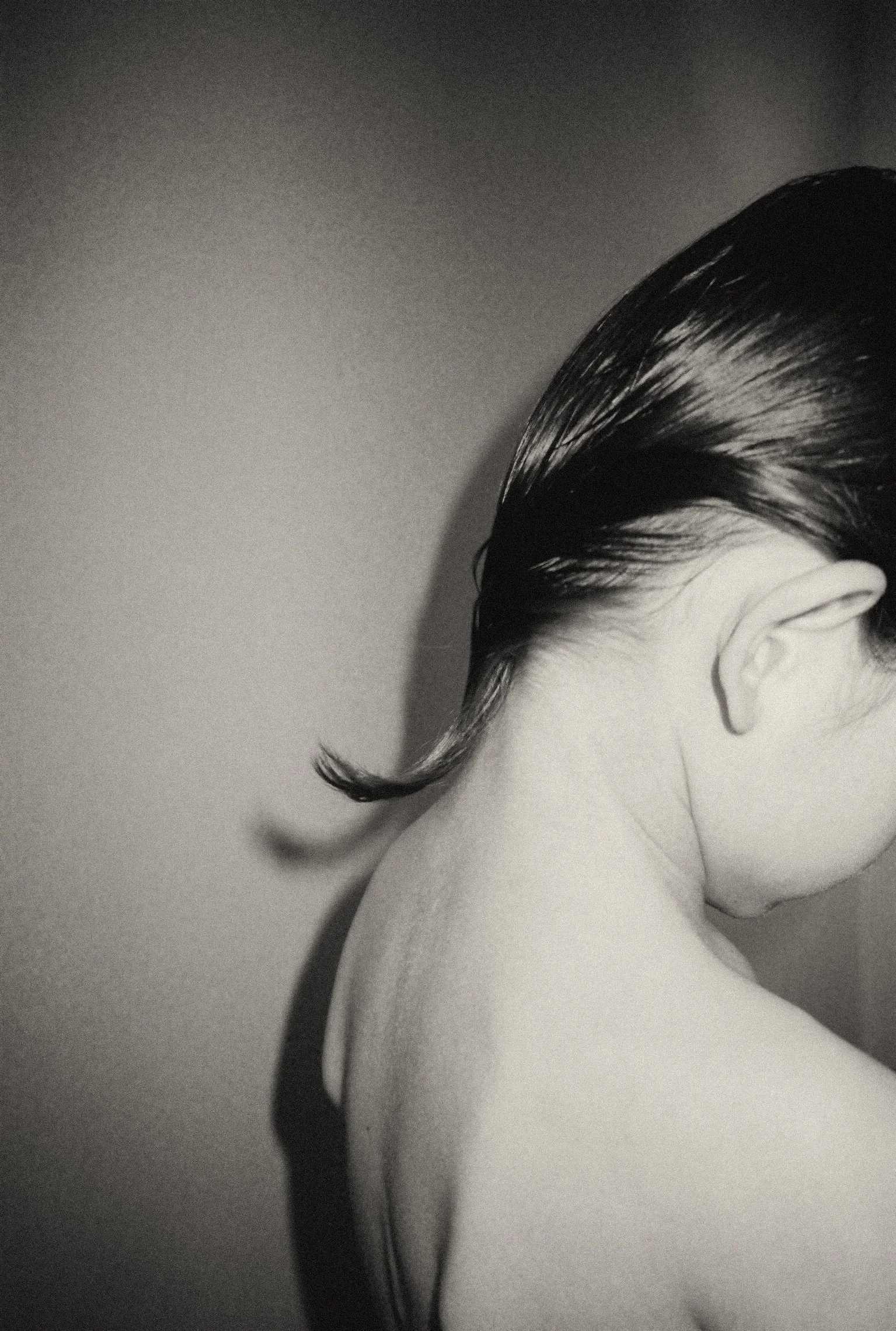 A grainy black and white film portrait of a child’s neck and hair, documenting the fleeting physical details of childhood growth and transformation.