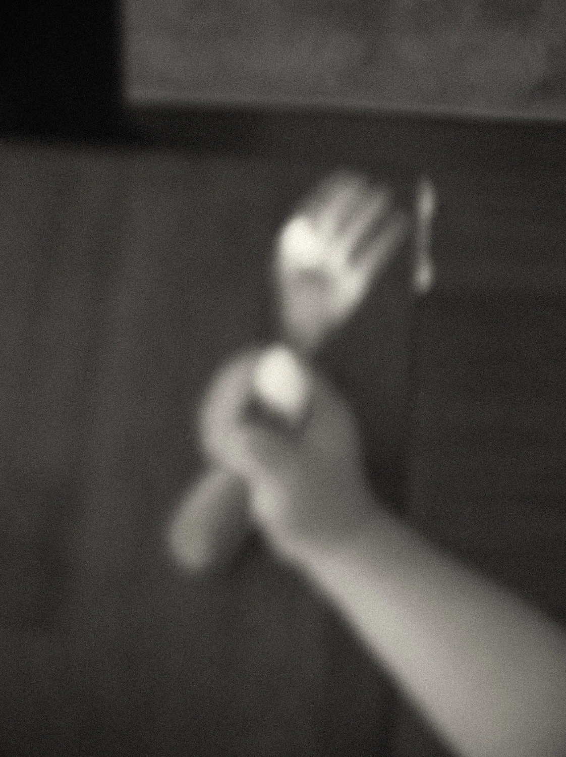 Black and white close up of a baby's small hand holding a spoon during their first solid food experience — a tender milestone moment captured in everyday family life. Family lifestyle photography by Noa Nguyen, Tokyo.