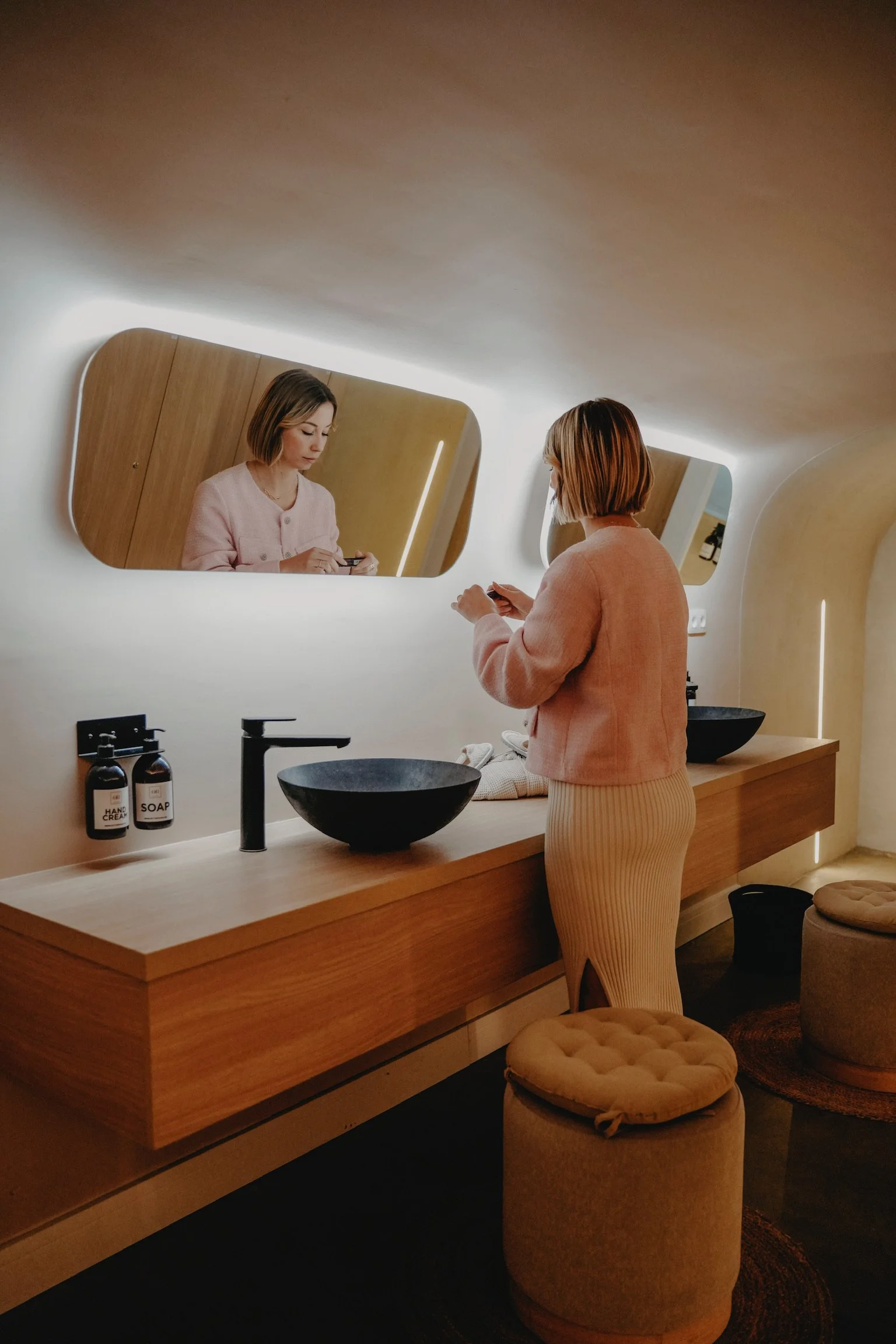 Femme en face d'un miroir dans une salle de bain moderne.