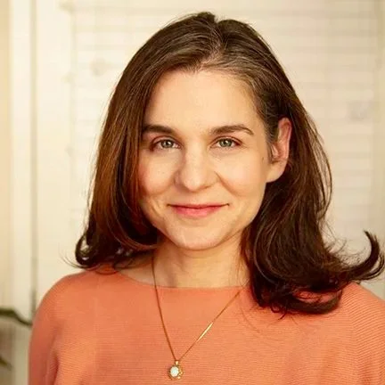 Photo of Dr. Liz Gustafson, clinical psychologist, a whiite woman with brown hair wearing a pink shirt and smiling at the viewer