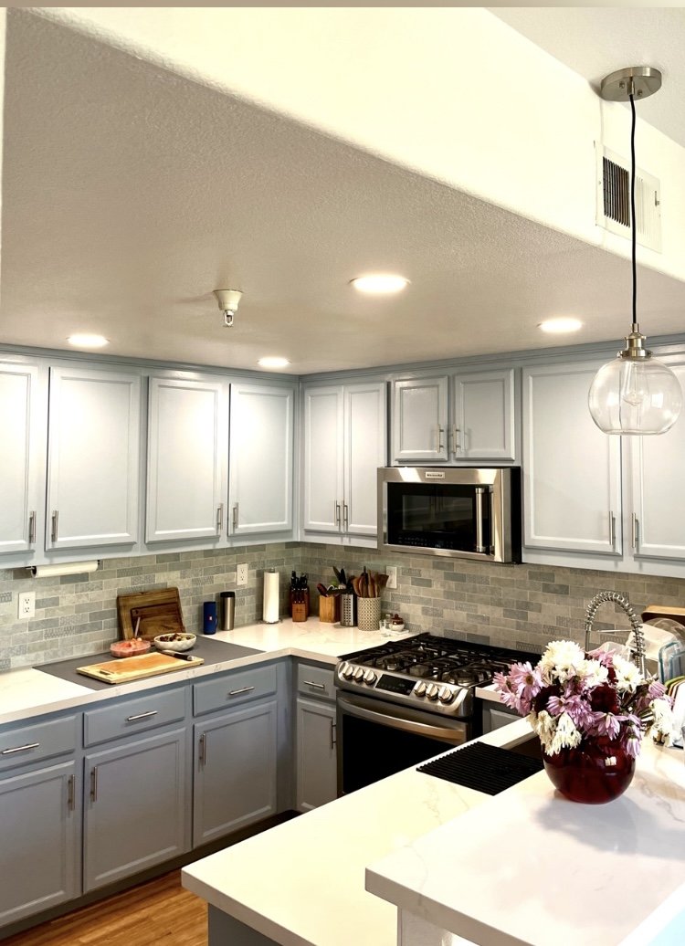 Modern kitchen with light gray cabinets, stainless steel appliances, and a vase of flowers