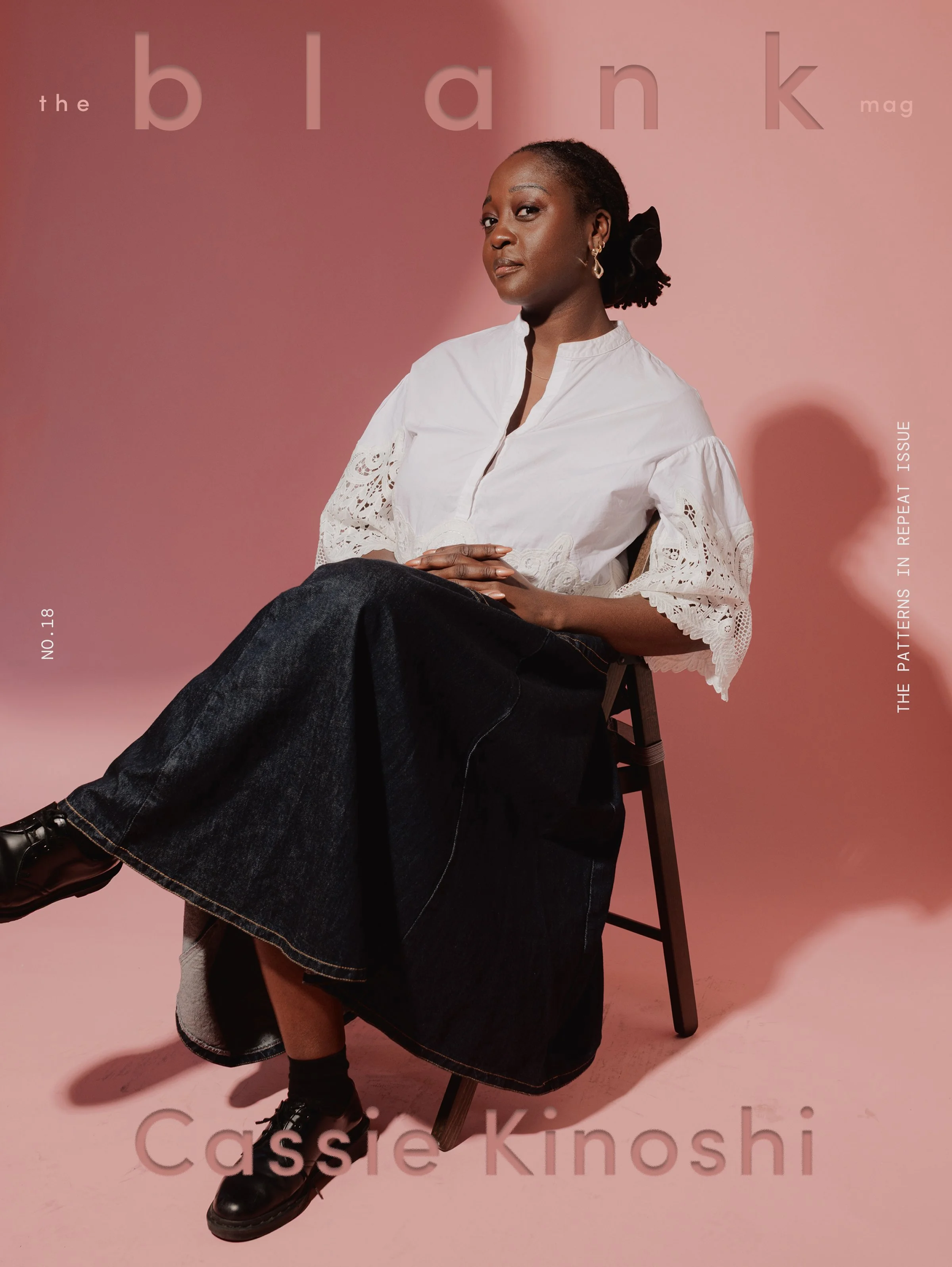 A woman sitting on a chair against a pink backdrop, looking at the camera. She wears a white blouse with lace details and dark jeans. The magazine title "the blank mag" is partially visible at the top, with the issue number 18 and the word "Cassie Kinosh" at the bottom.