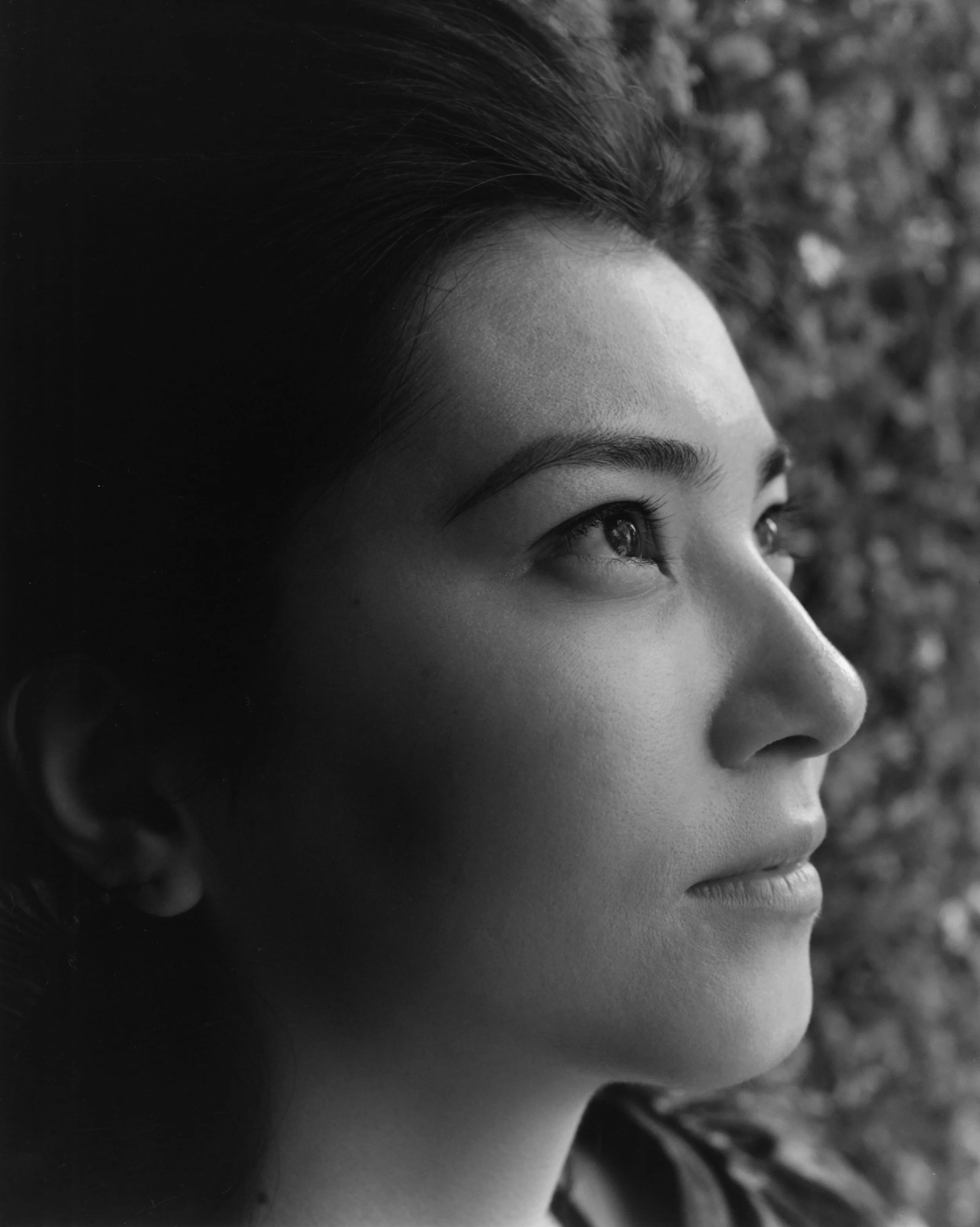 Close-up of a woman's face in profile looking upwards, with a blurred background.