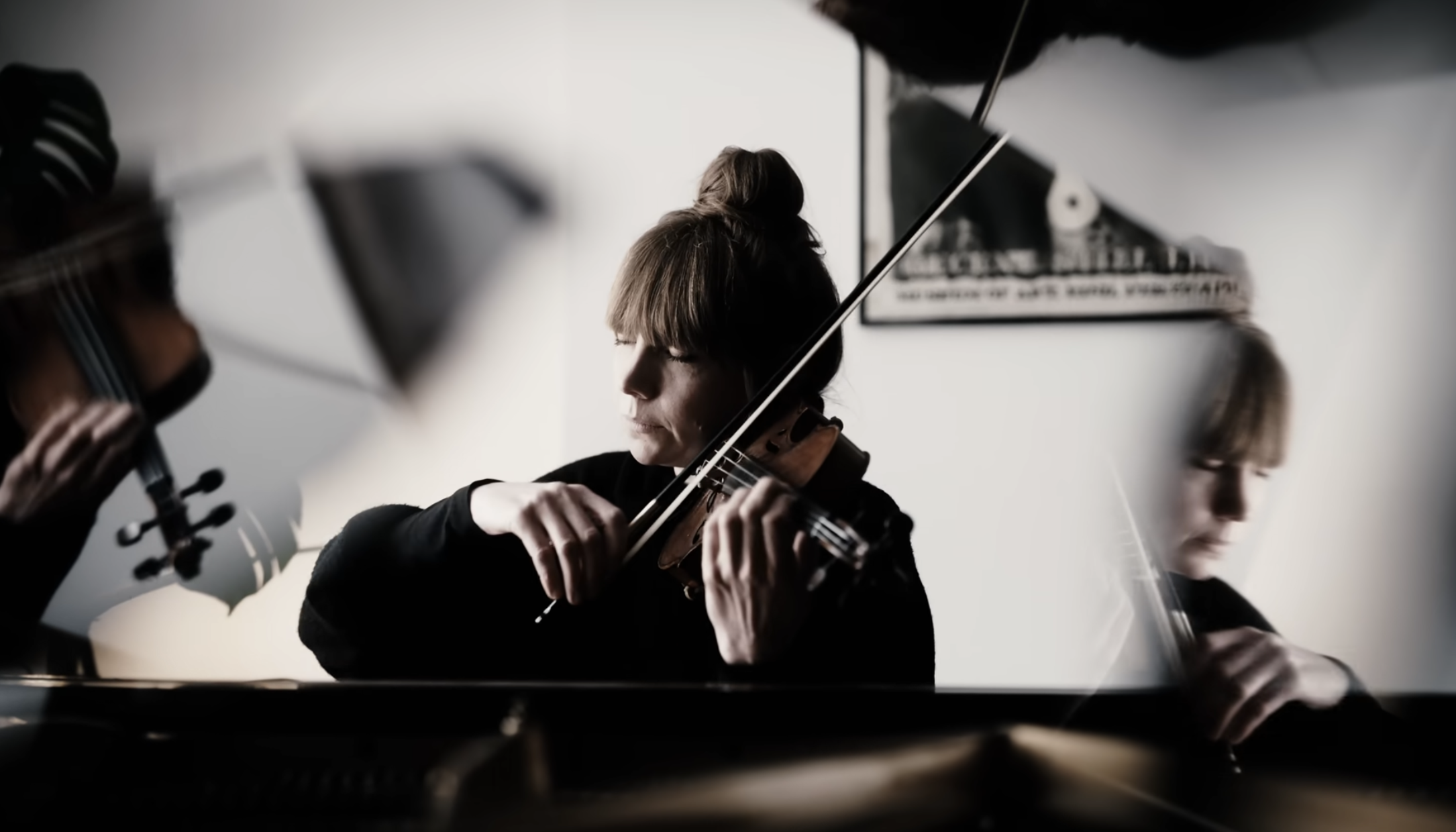 Two women playing violins in a room, with filters creating motion blur effects.
