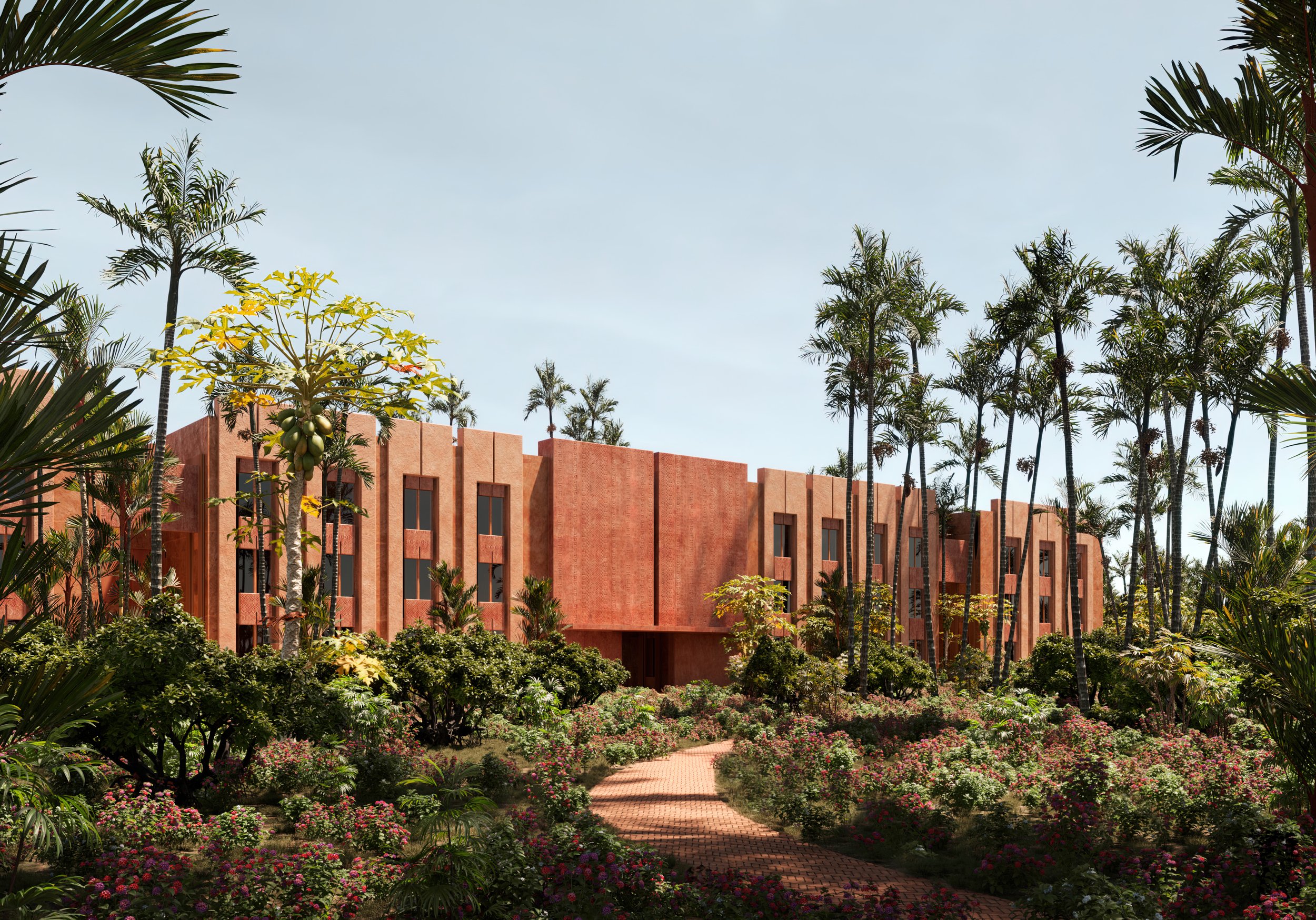 Edificio de color terracota rodeado de jardines con flores y palmeras, camino de ladrillos en primer plano, cielo despejado.