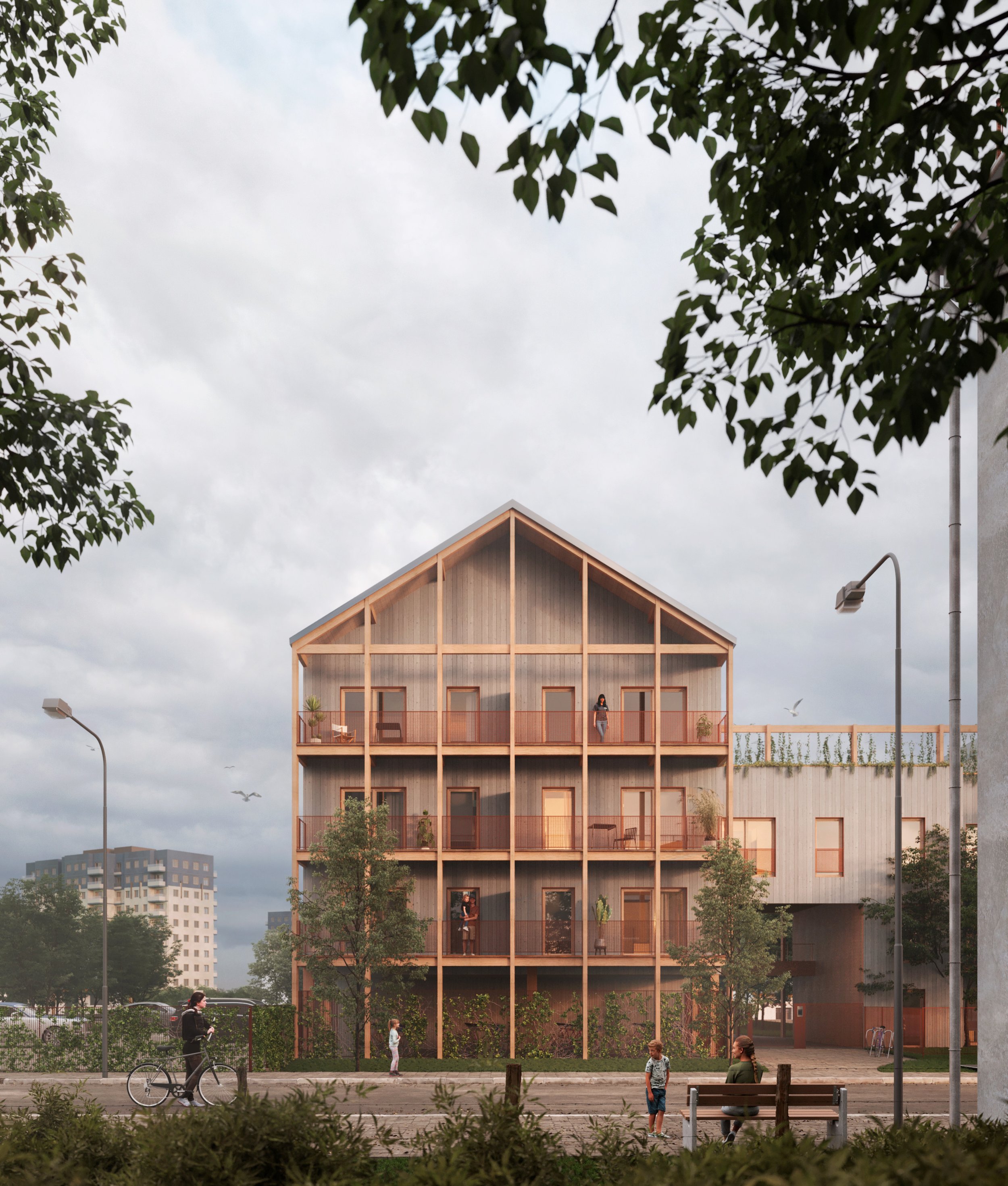 Edificio moderno de varias plantas con estructura de madera visible, balcones y ventanas. Personas caminando en la acera y parque con árboles y bancos, luces de calle y edificios en el fondo bajo cielo nublado.