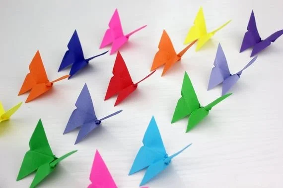 Colorful origami butterflies arranged on a white surface.