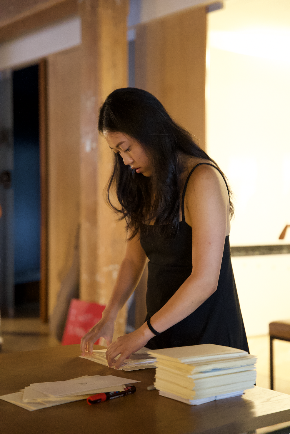 Woman organizing papers on a table indoors.