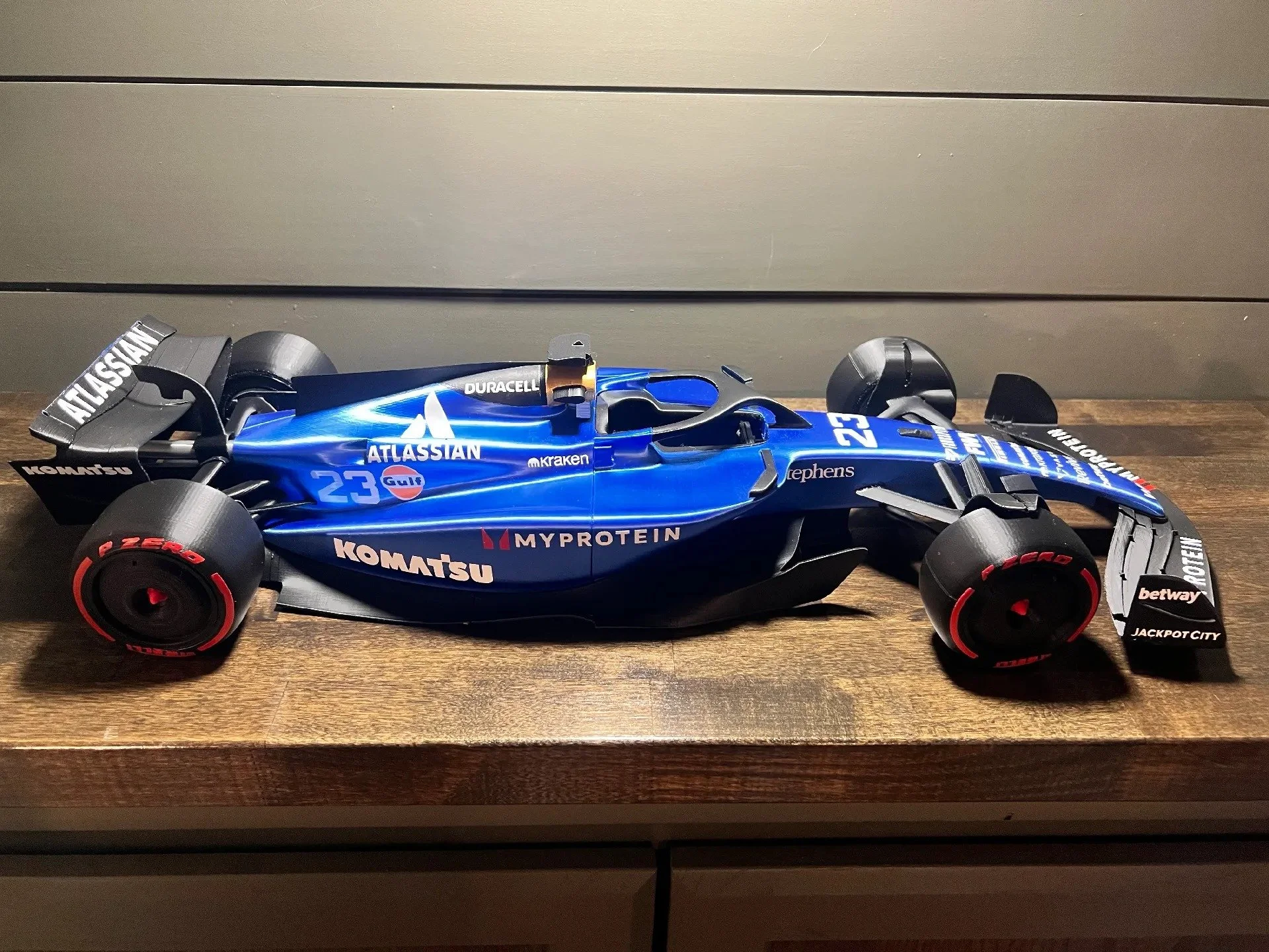 A blue 3D-printed Formula 1 inspired racecar model. Detailed with a Williams style/inspired livery with black accents and white sponsors