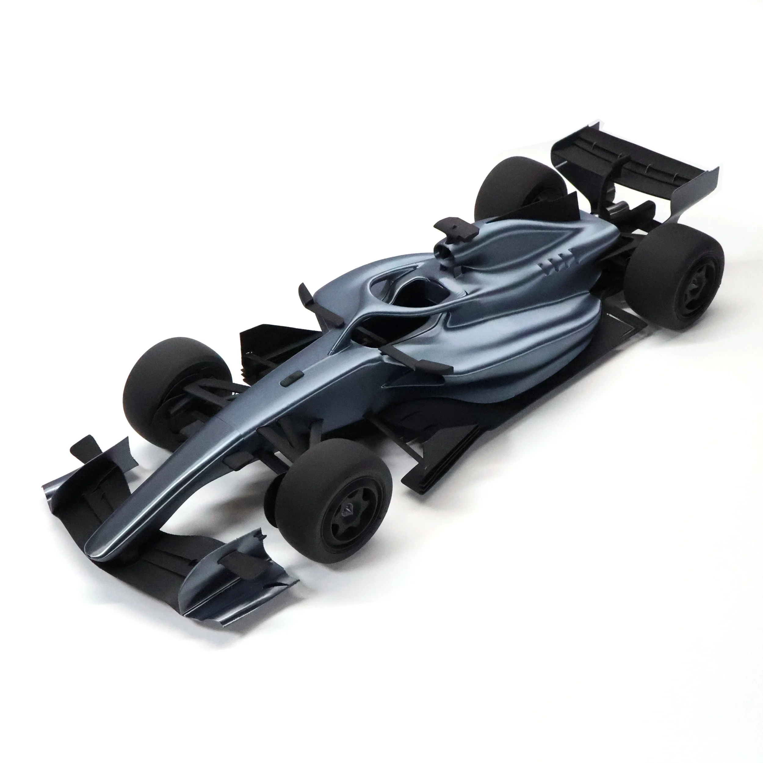 Model Formula 1 race car in gray and black with large rear wing, racing tires, and aerodynamic design.